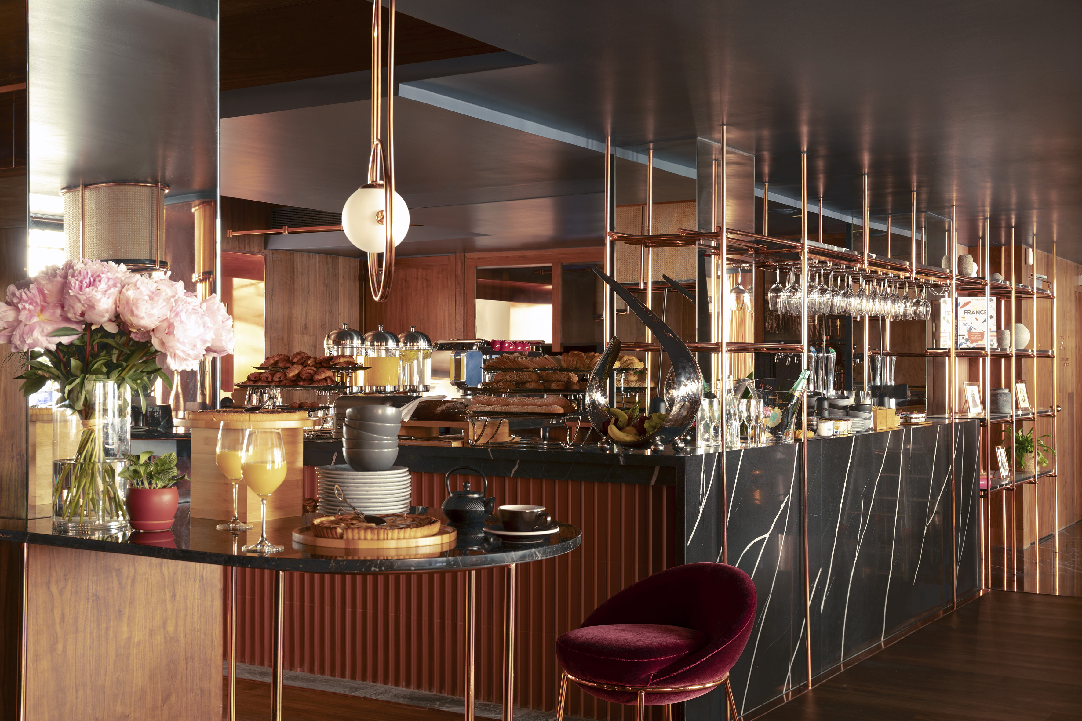 Modern breakfast buffet with black marble counter, copper accents, and fresh pastries.
