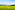 a green field with trees and mountains in the background