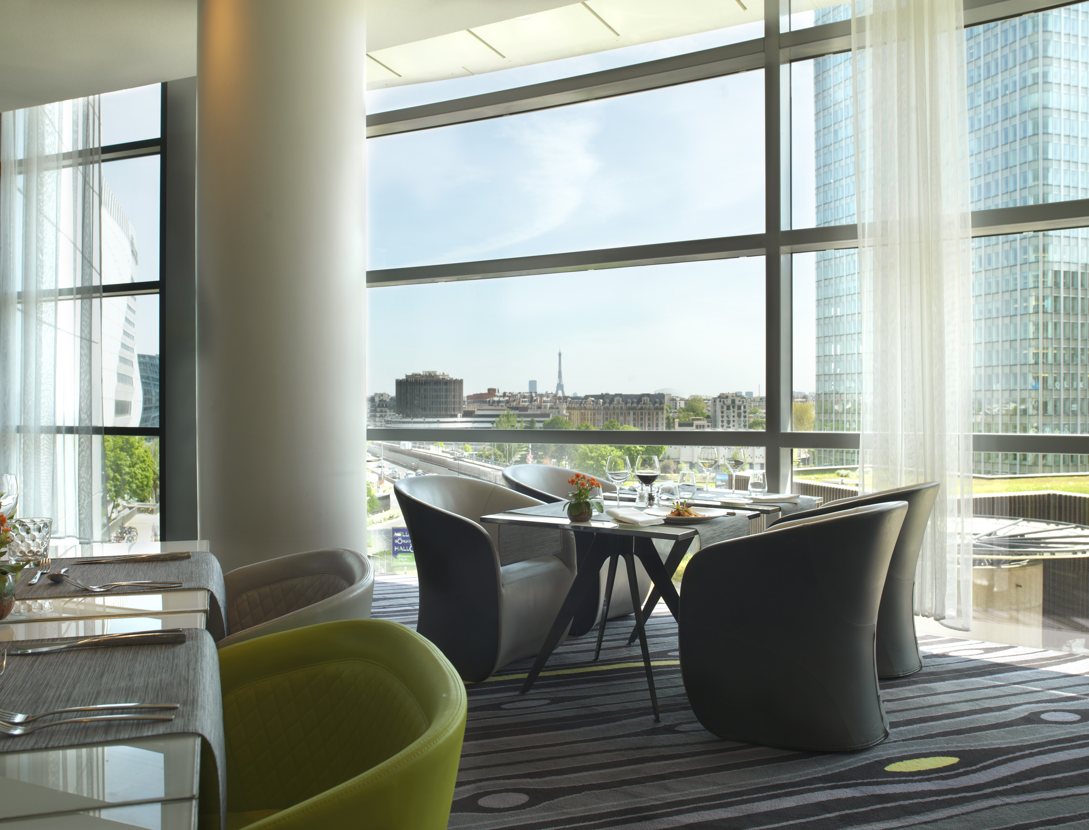 Modern restaurant with city view of Paris skyline and distant Eiffel Tower.