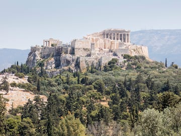 a stone building on a hill with trees