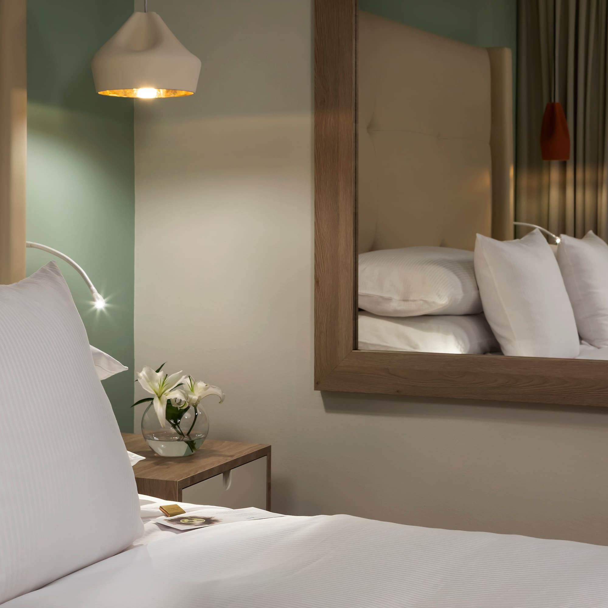 a bed with white pillows and a mirror in the background