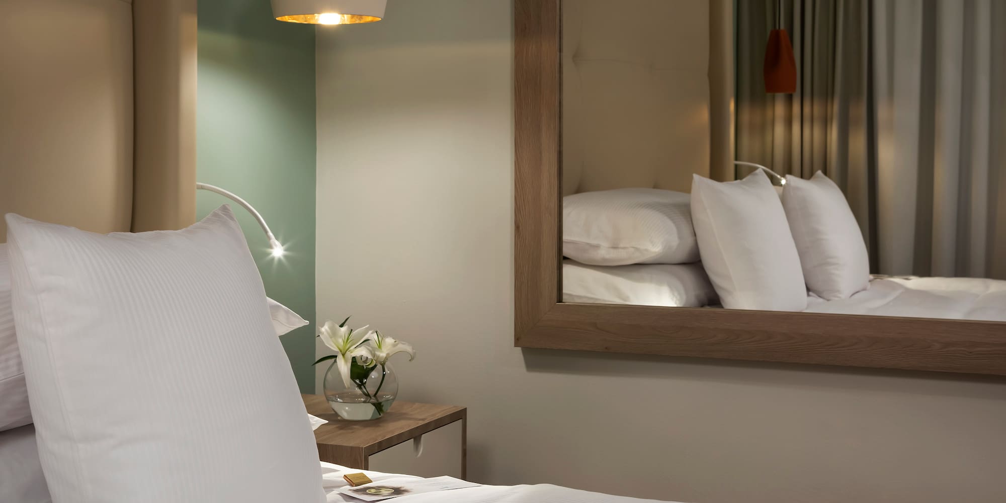 a bed with white pillows and a mirror in the background