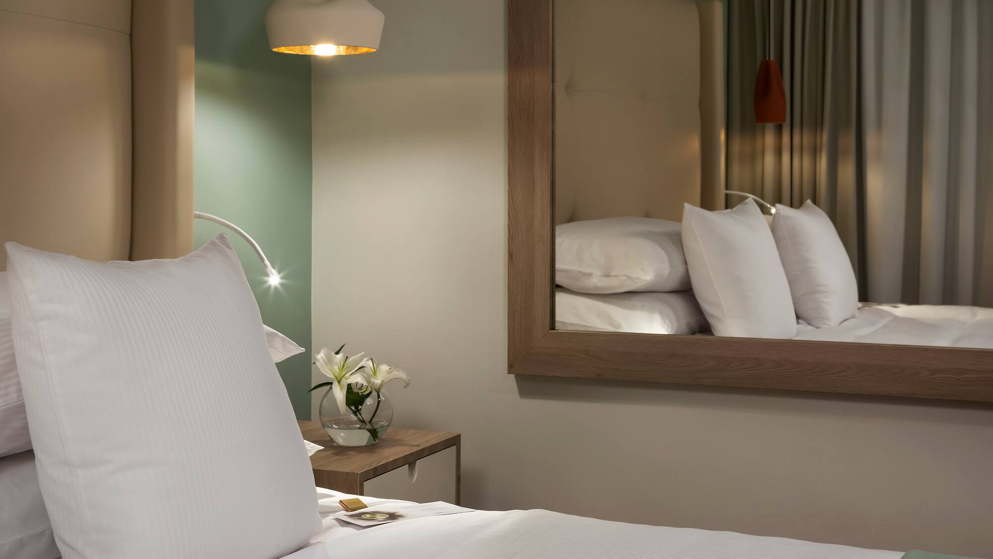 a bed with white pillows and a mirror in the background