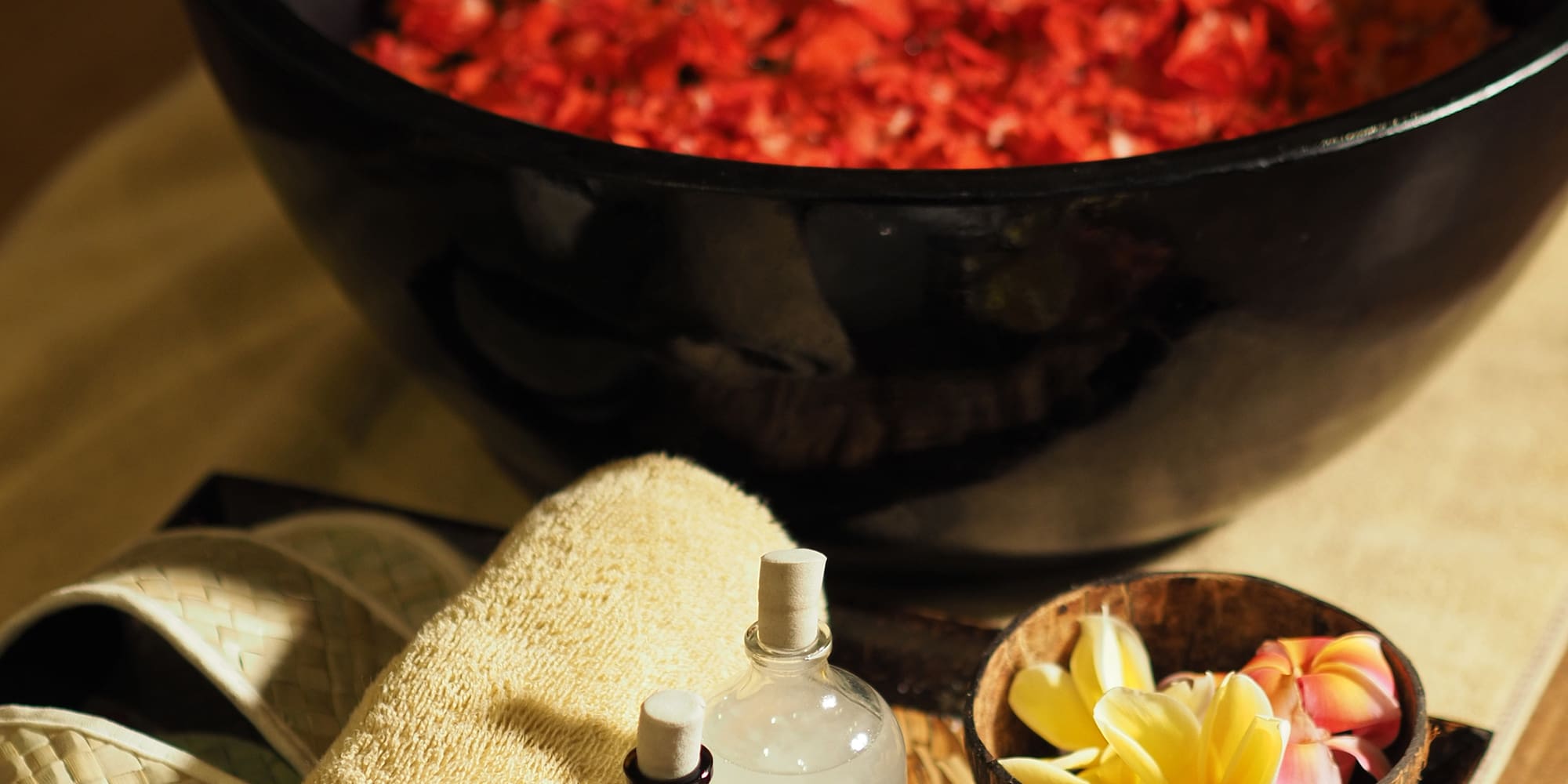 a bowl of red petals and a towel and a bottle of salt