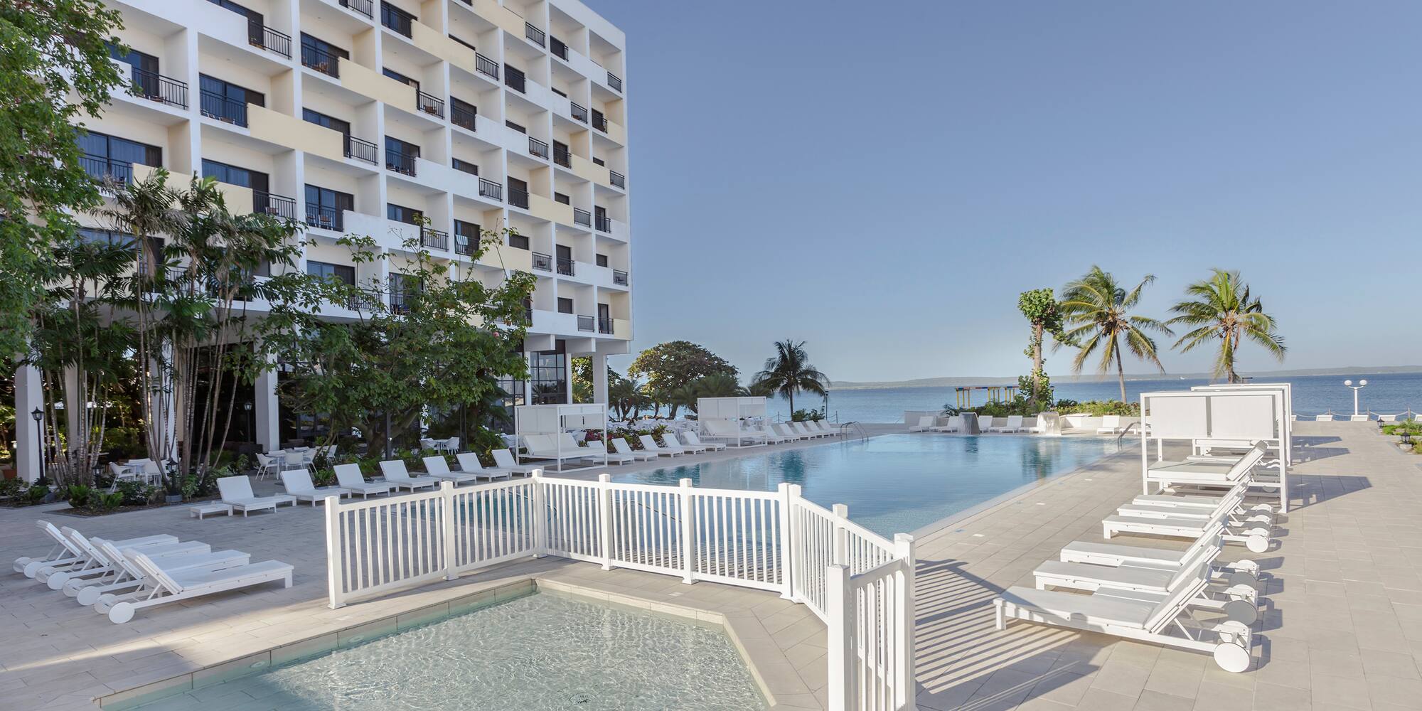 a pool with lounge chairs and a building in the background