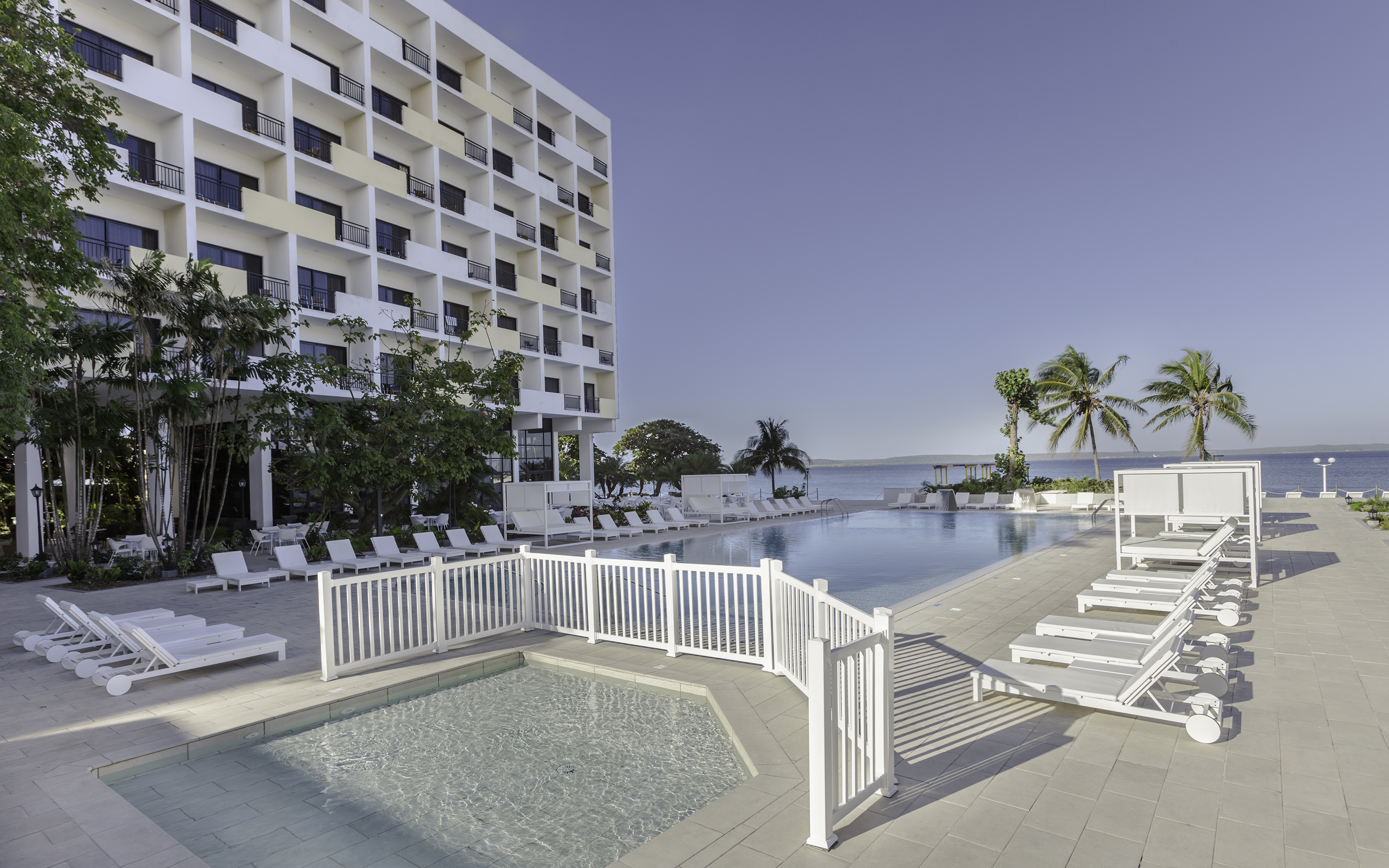 a pool with lounge chairs and a building in the background