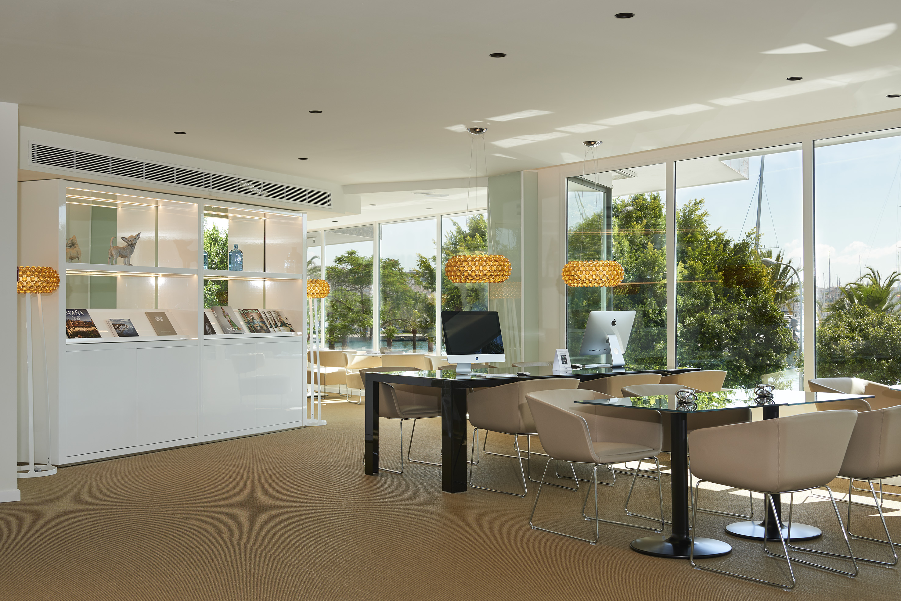 Modern lounge with computers, elegant chairs, and marina view.