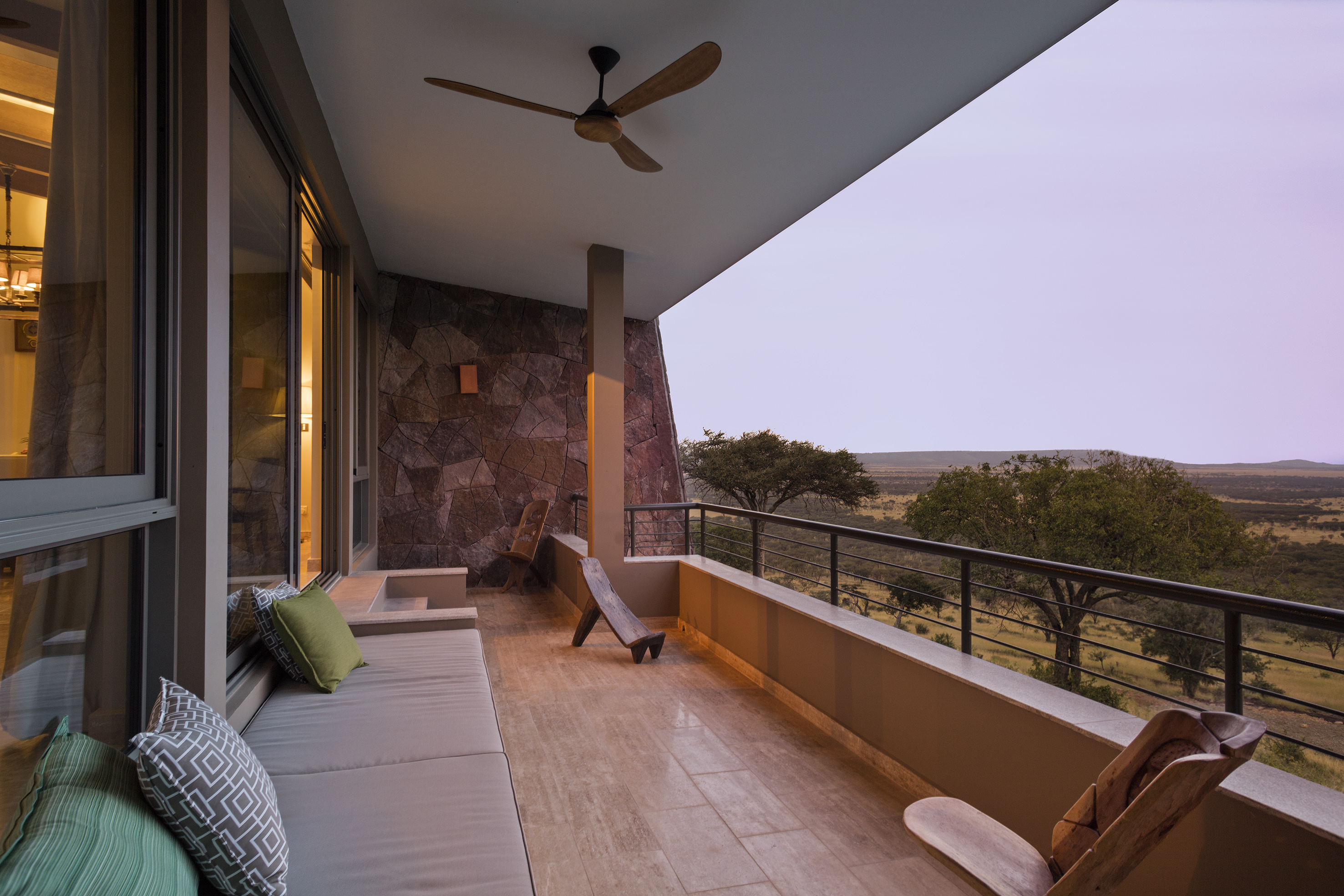 Luxury lodge balcony with outdoor seating and African savanna view.