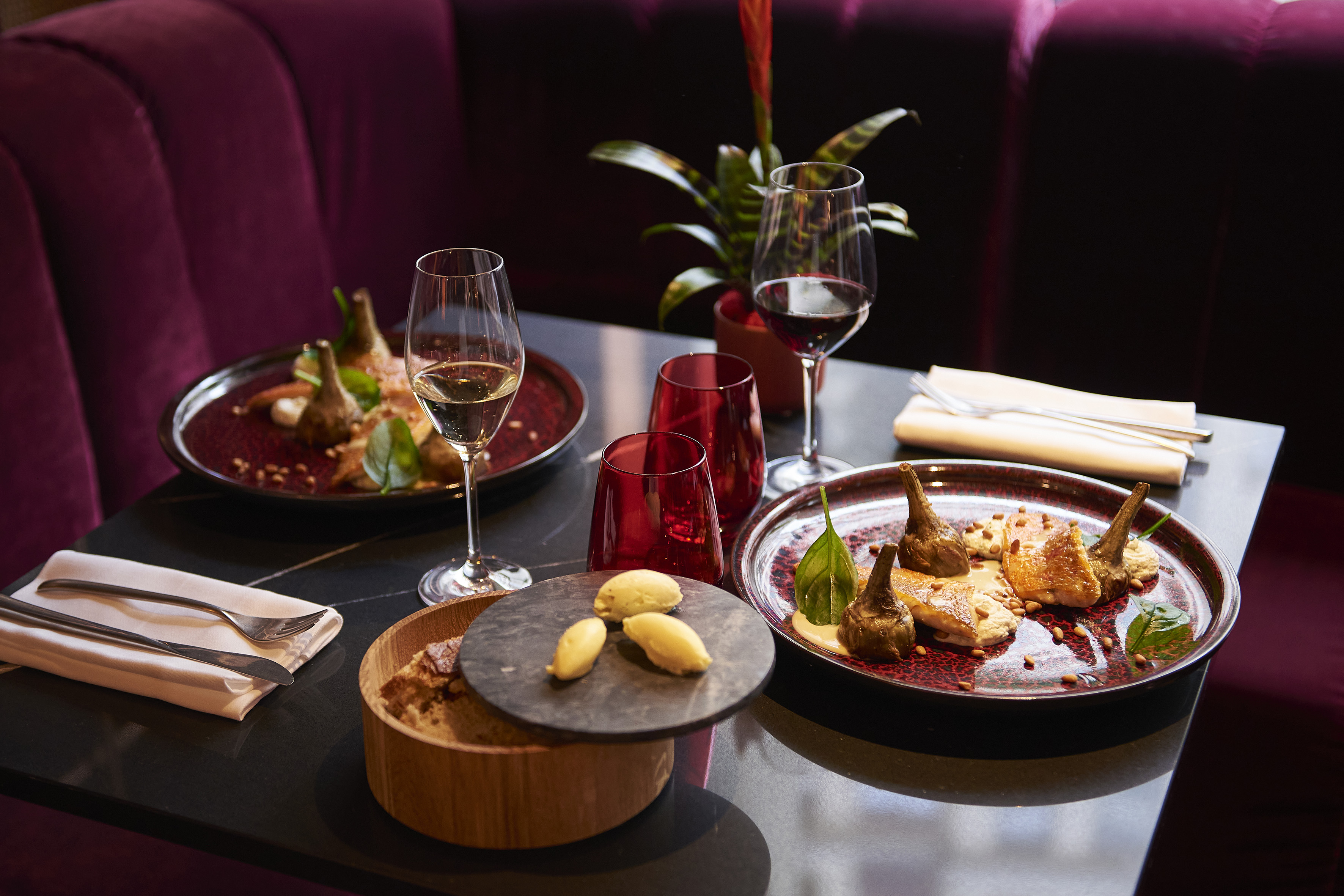 a table with plates of food and wine glasses