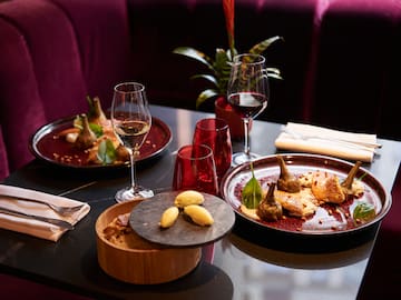 a table with plates of food and wine glasses
