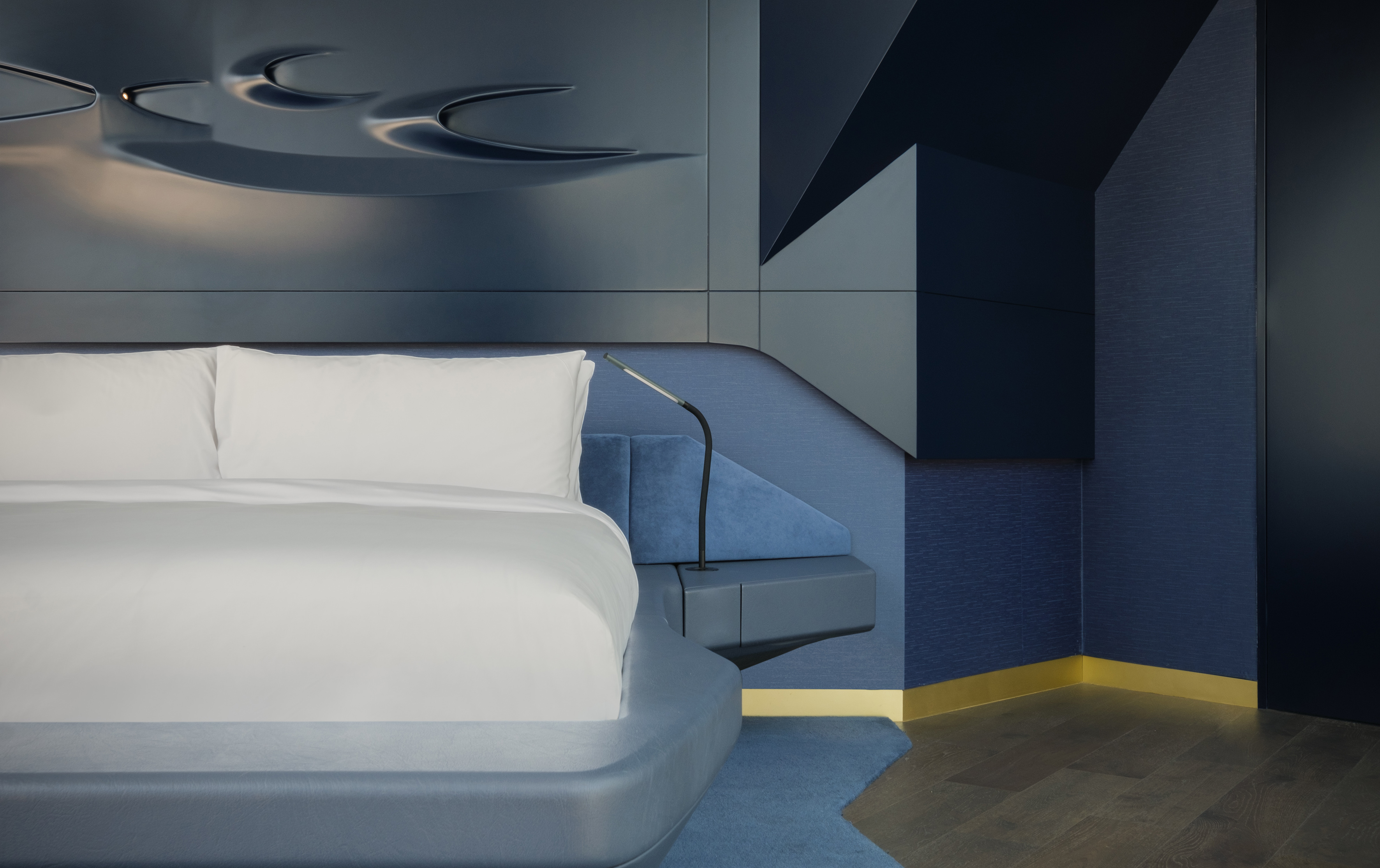 Modern blue bedroom with sculpted headboard and geometric wall design.