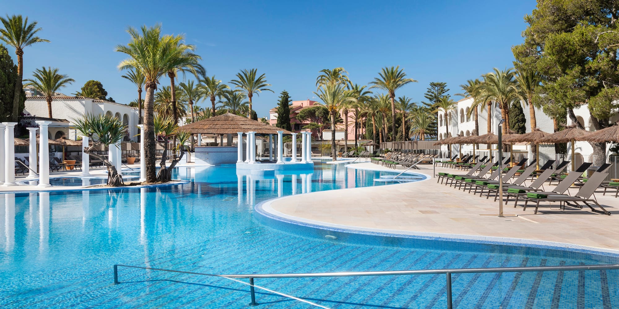 a pool with palm trees and a building