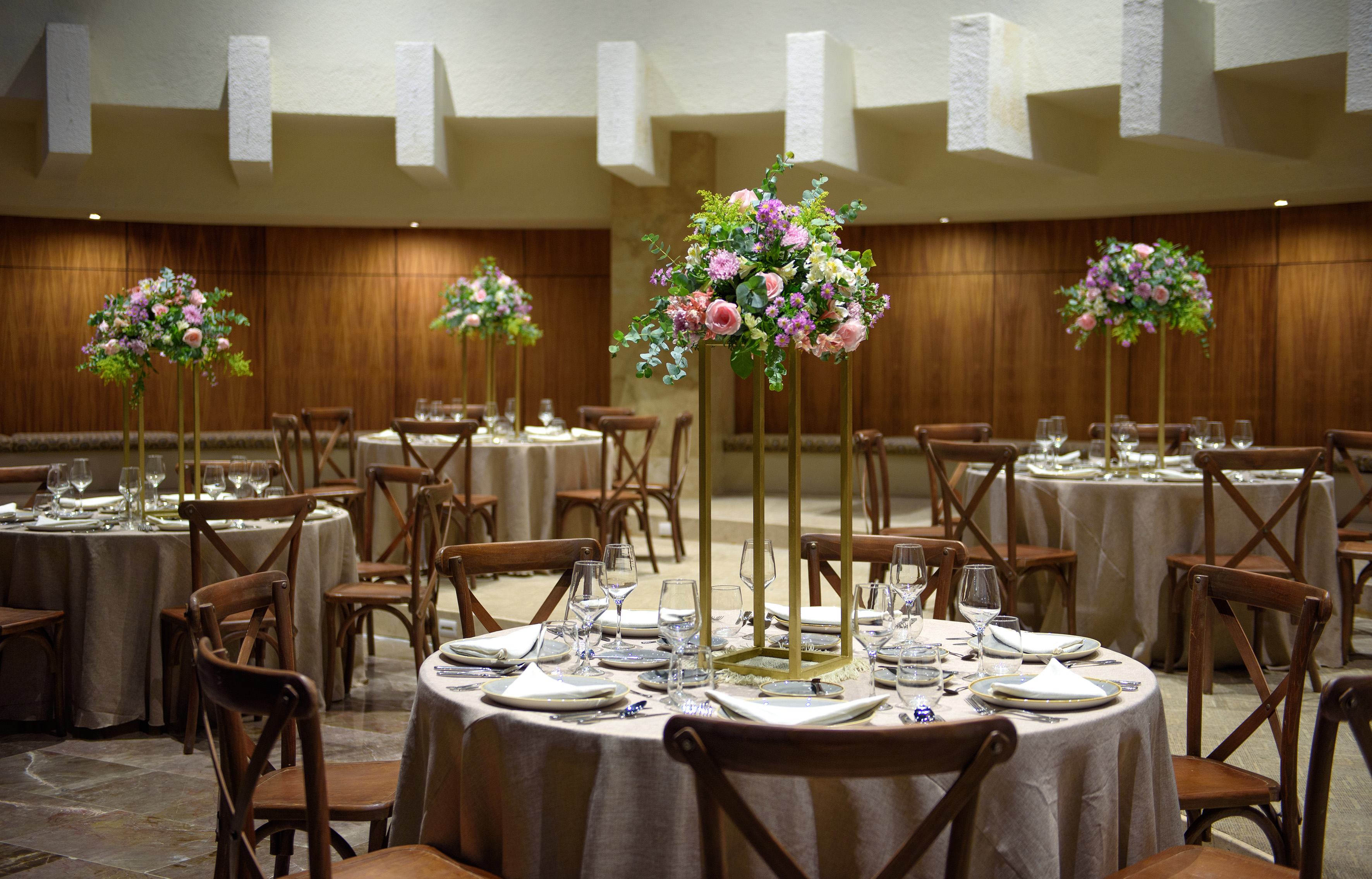 Elegant event tables with floral centerpieces and wood cross-back chairs.