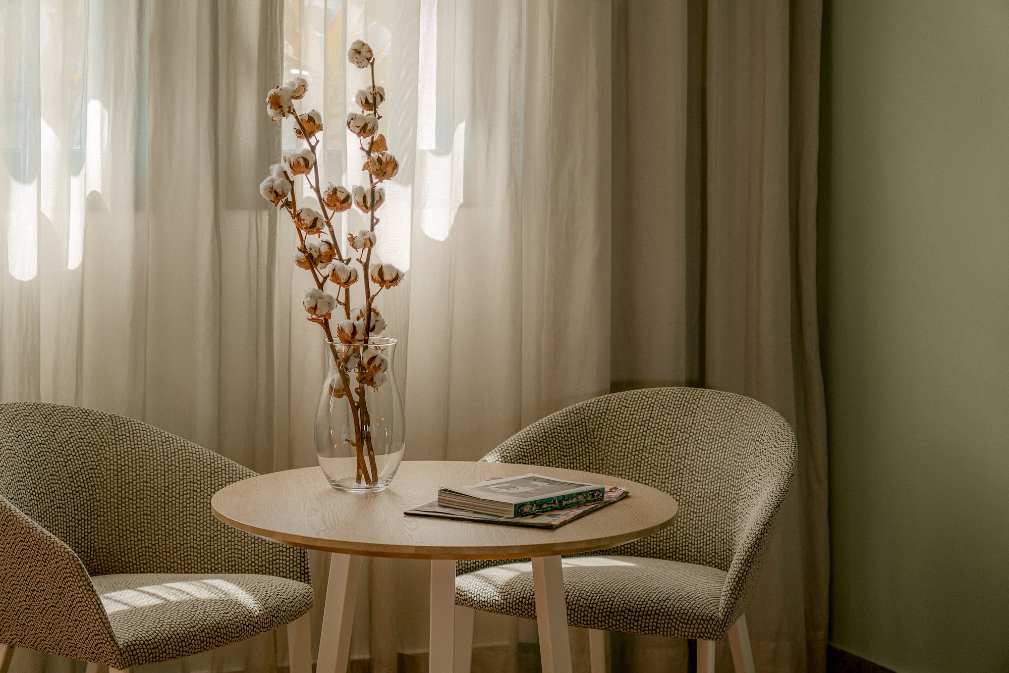a table with a vase of cotton flowers and a book