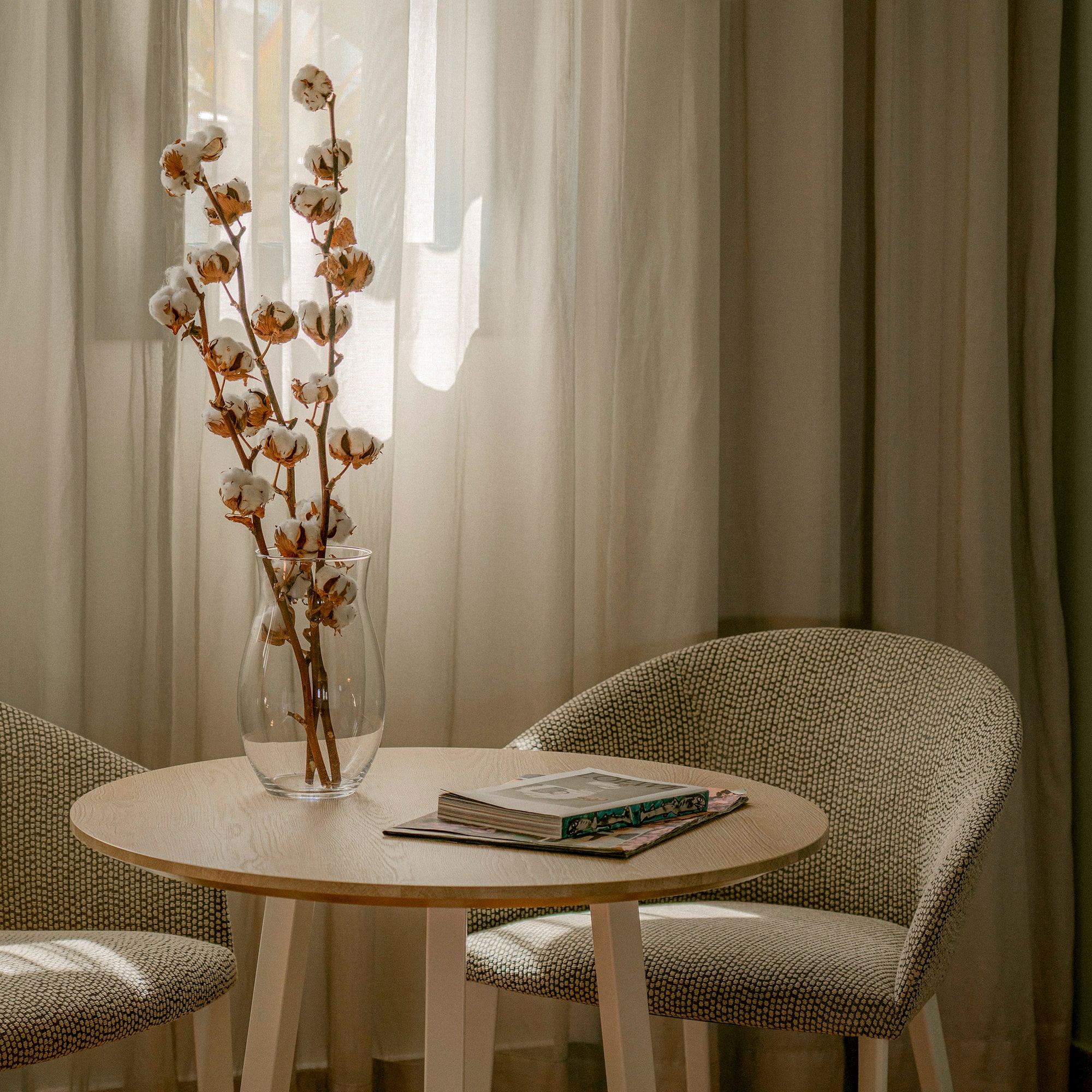 a table with a vase of cotton flowers and a book