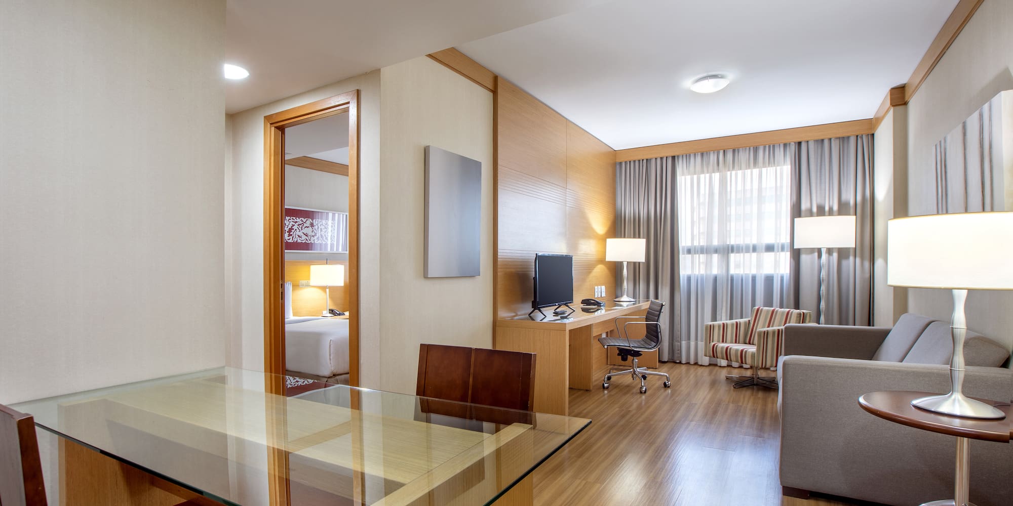 a room with a glass table and a desk and chairs