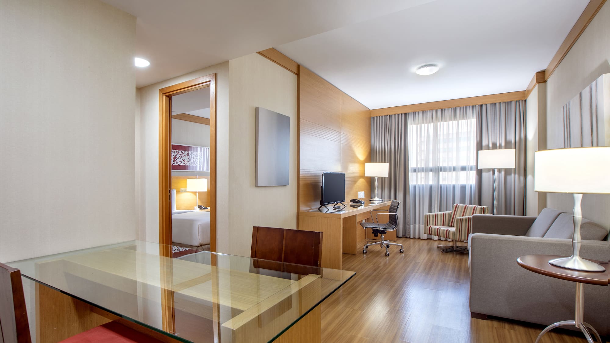 a room with a glass table and a desk and chairs