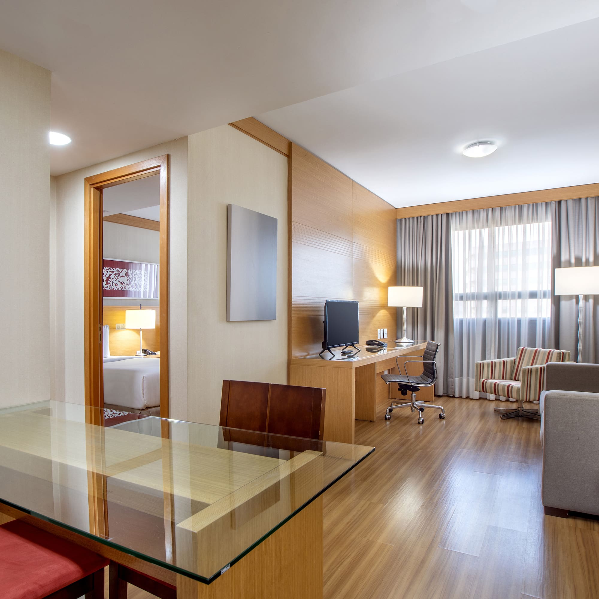 a room with a glass table and a desk and chairs