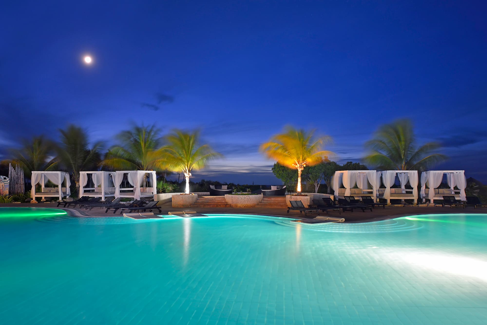 a pool with palm trees and a deck chair