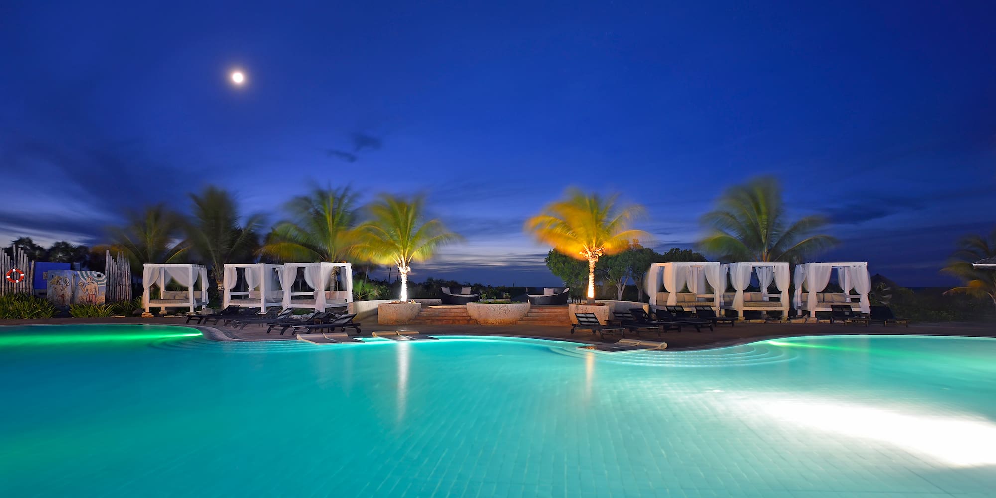 a pool with palm trees and a deck chair