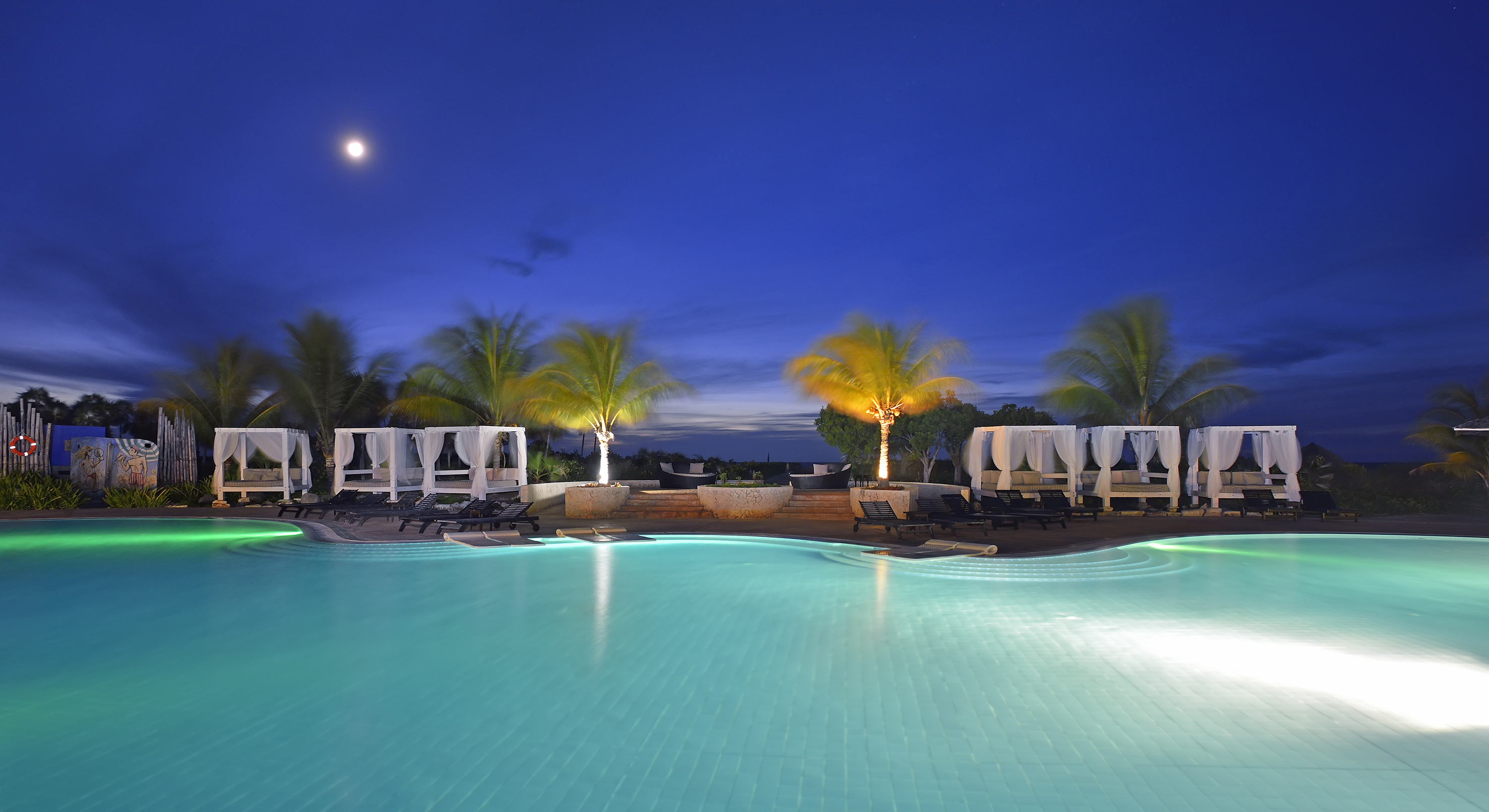 a pool with palm trees and a deck chair