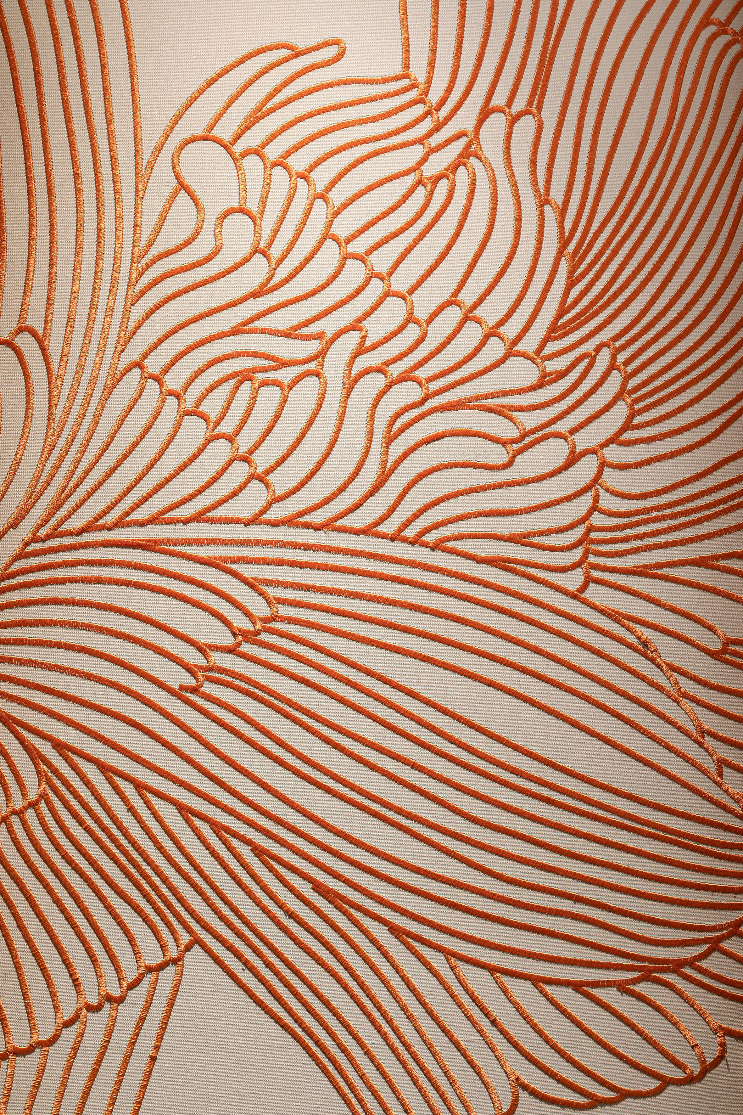 Orange embroidery on beige fabric with an abstract pattern.