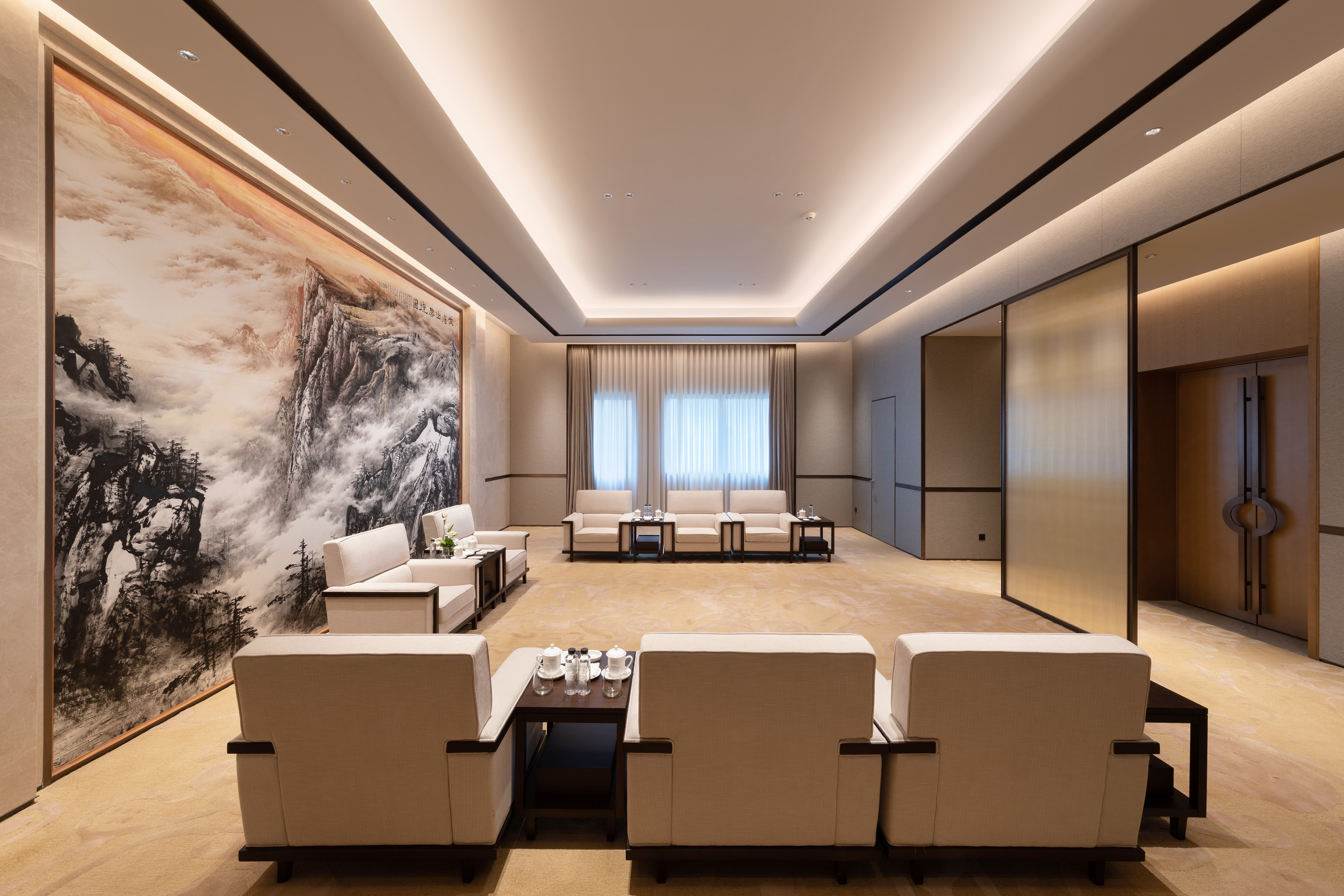Executive lounge with traditional Chinese mountain mural and modern beige seating.