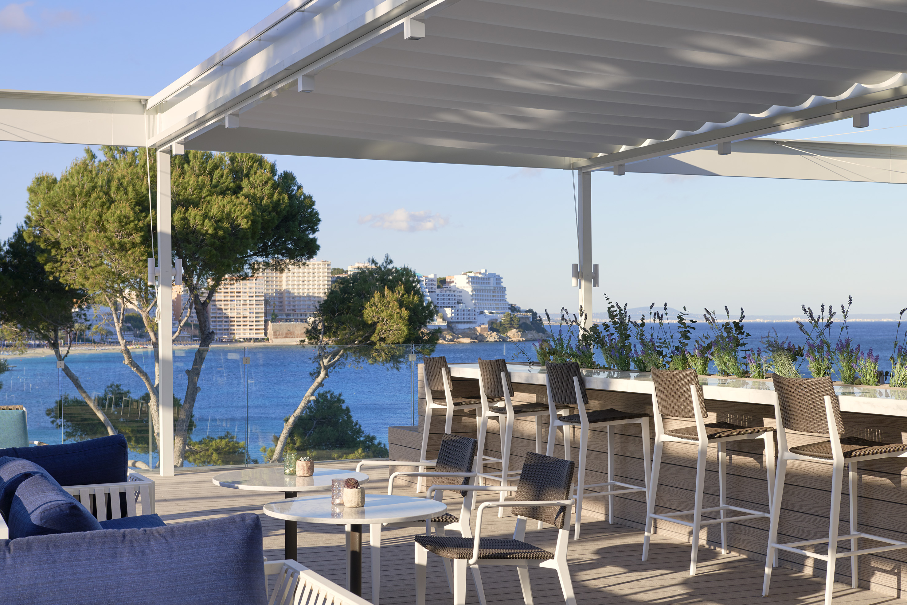 Outdoor terrace with retractable pergola, lounge seats, bar, and sea view.