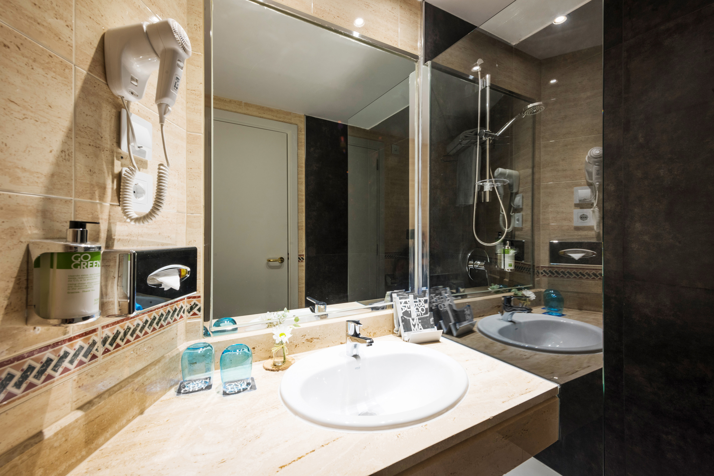 Contemporary hotel bathroom vanity with sink, mirror, and mounted hair dryer.