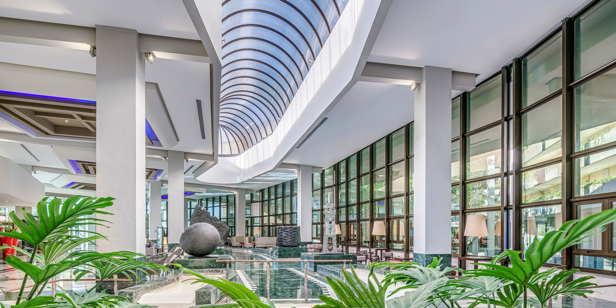a large indoor building with glass walls and plants