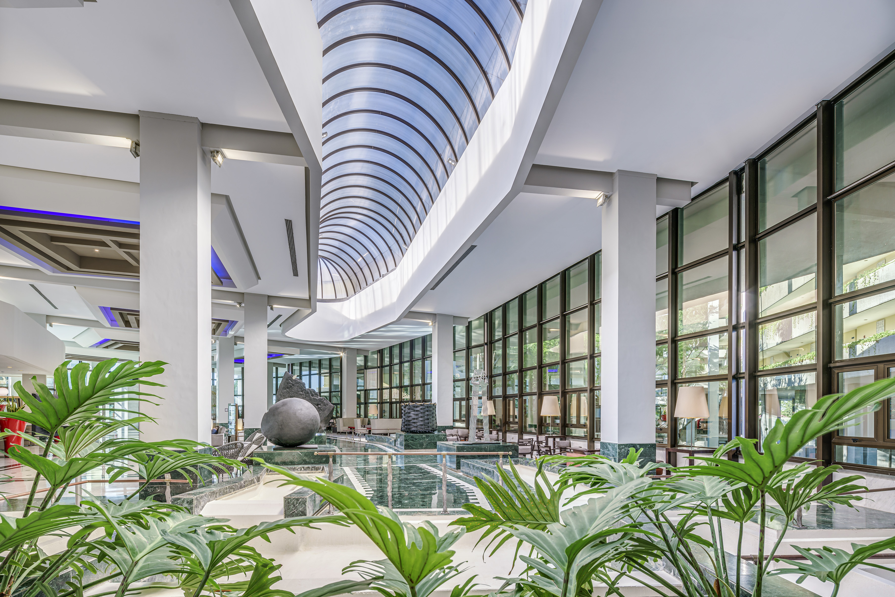 a large indoor building with glass walls and plants