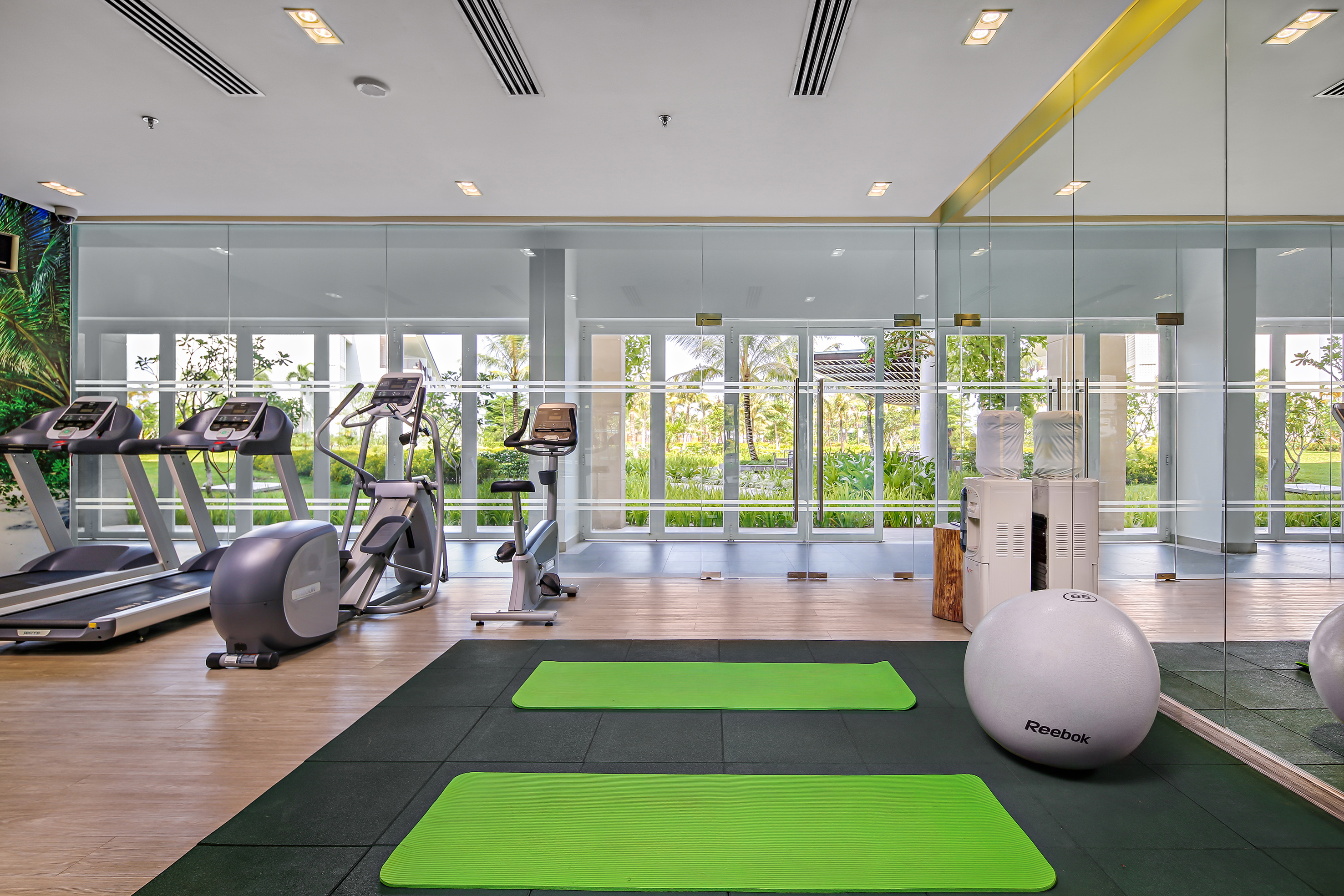 Bright modern gym with cardio machines, yoga mats, and stability ball.
