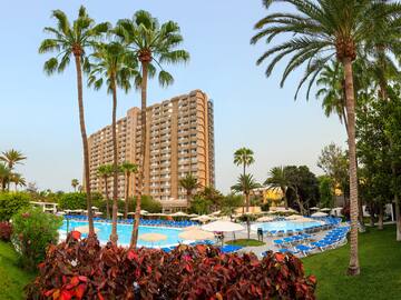 a pool with palm trees and a building in the background
