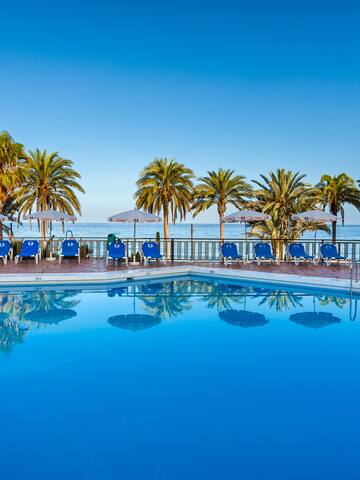 a pool with chairs and umbrellas by the water