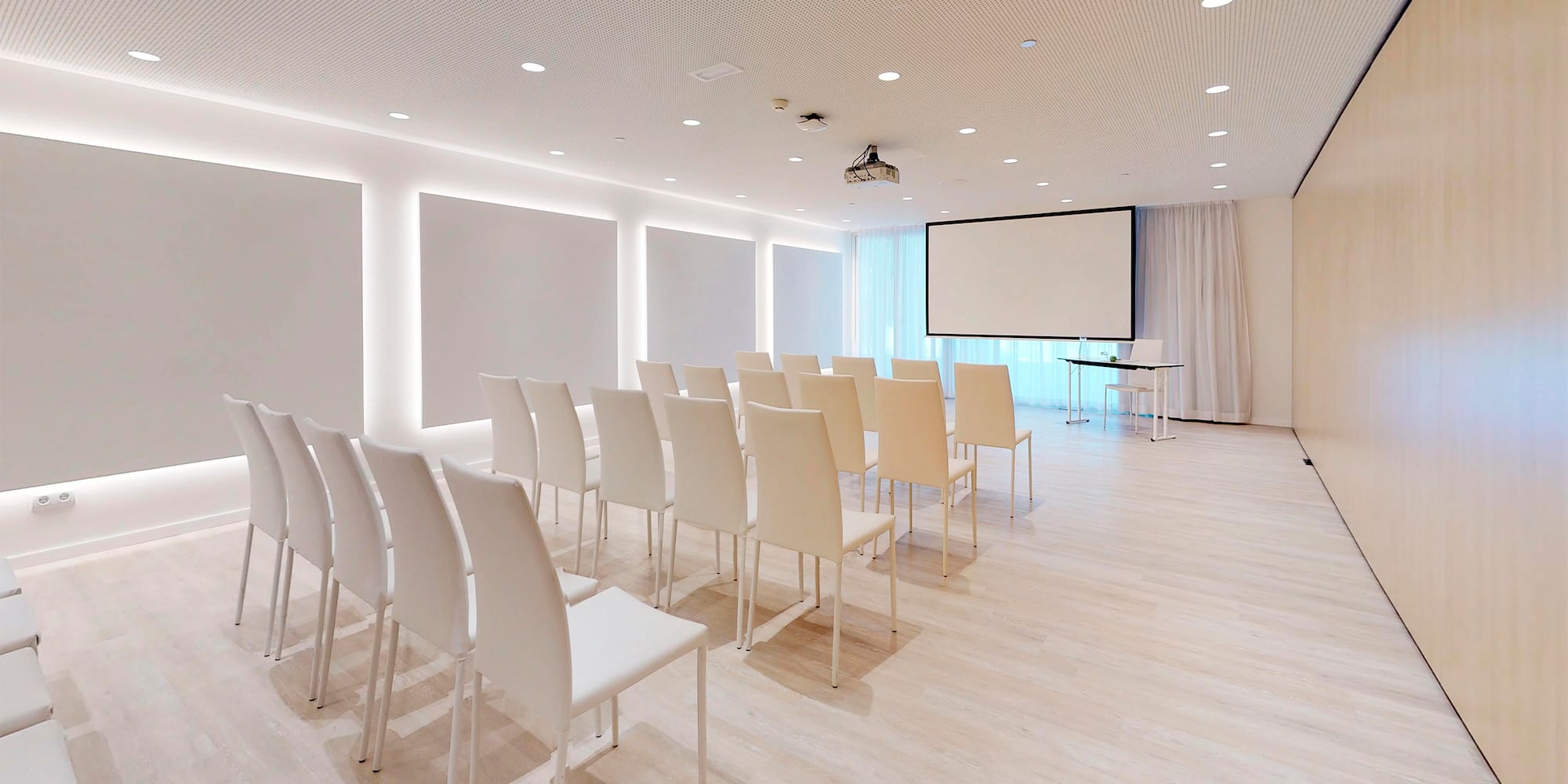 a room with white chairs and a projector screen