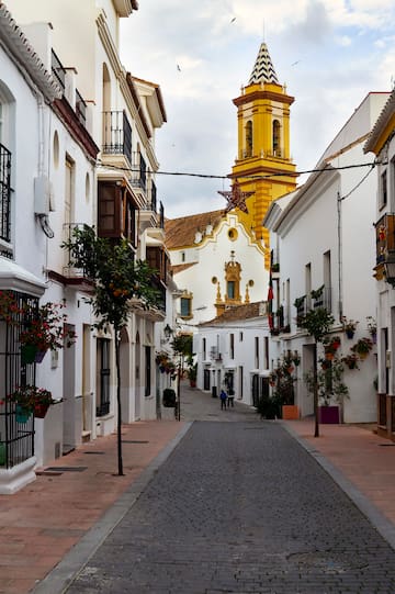 a street with white buildings and a yellow tower