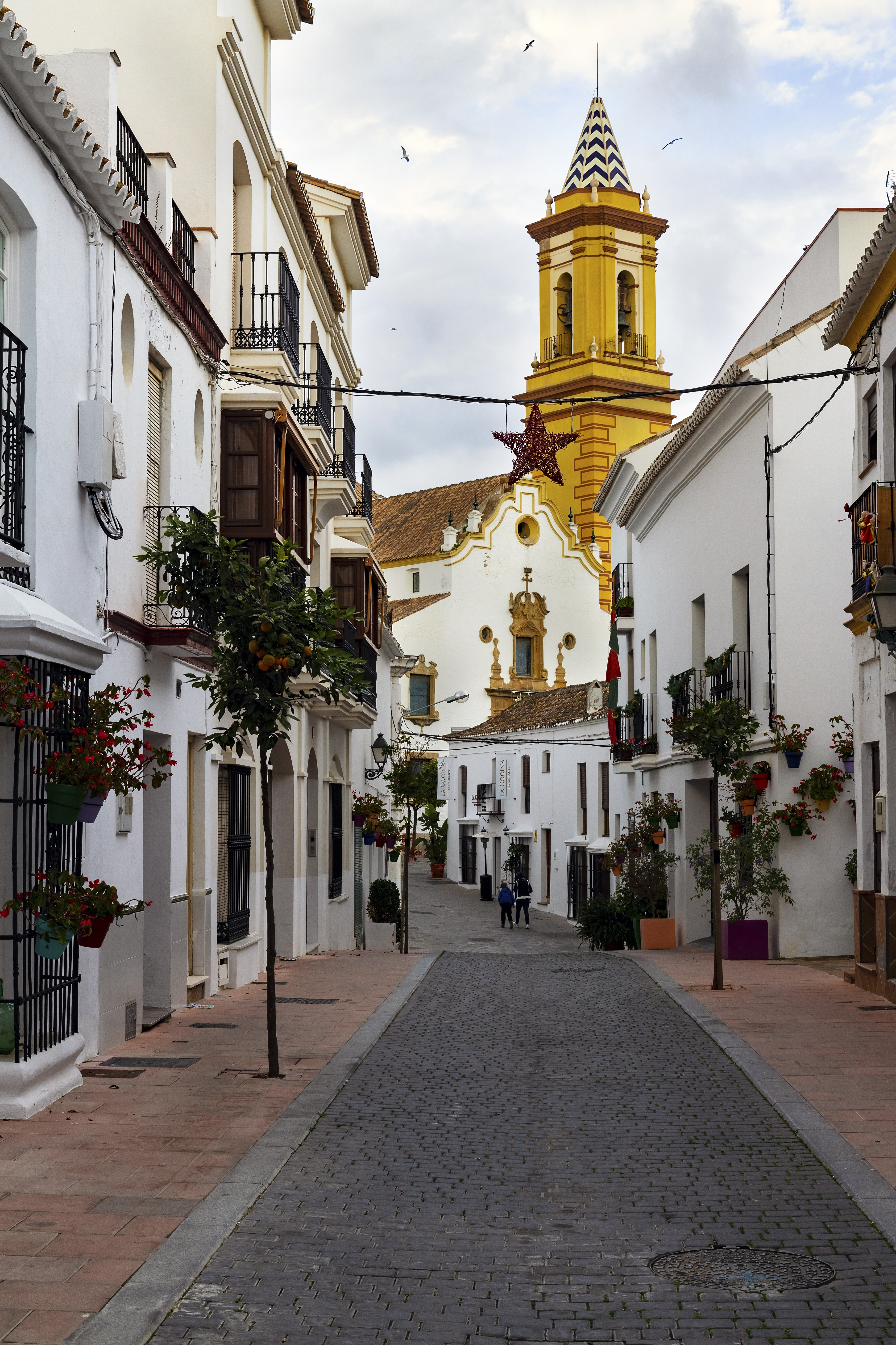a street with white buildings and a yellow tower