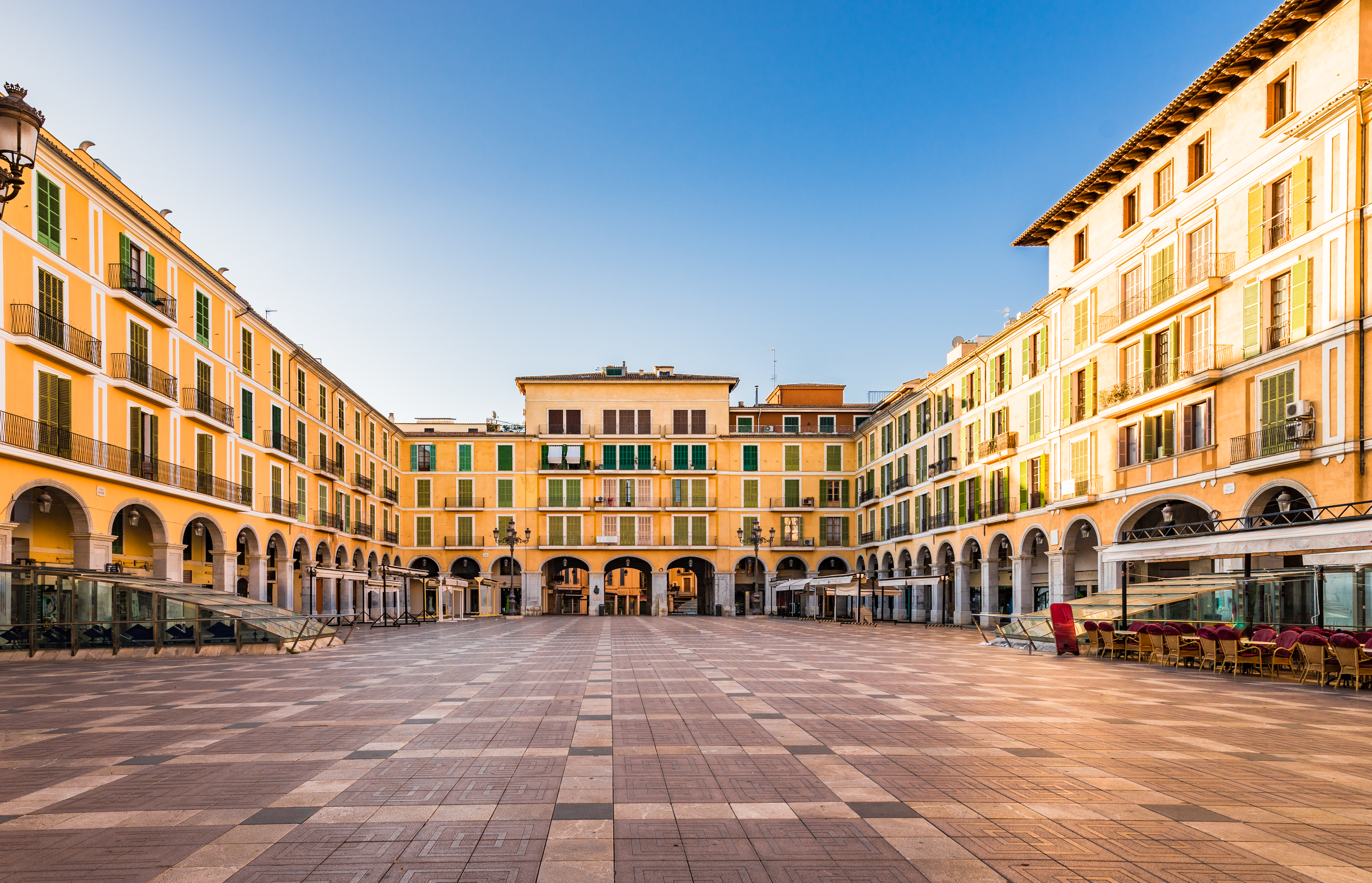 Palma de Mallorca Plaza Mayor, large empty square with yellow arcaded buildings.