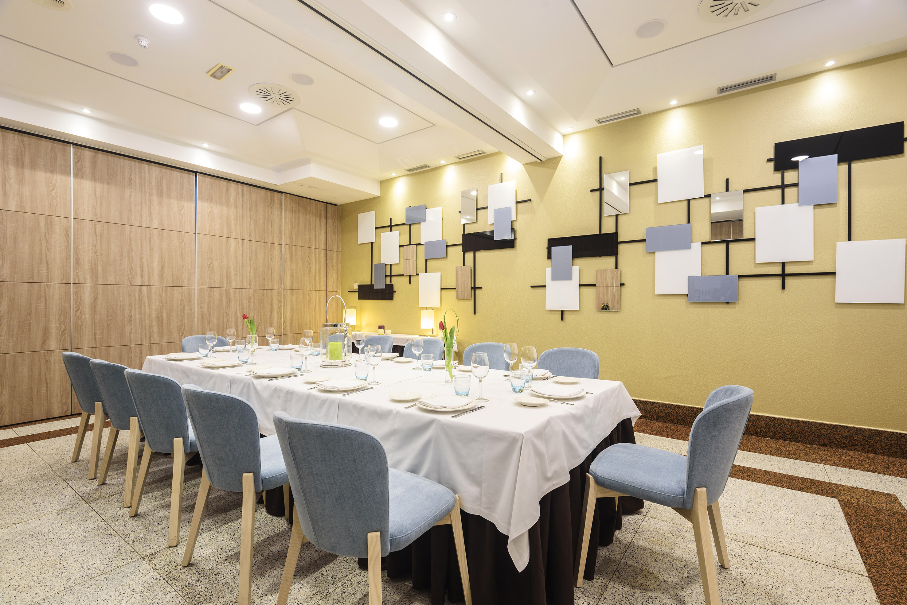 Hotel private dining room with large table, blue chairs, and modern decor.