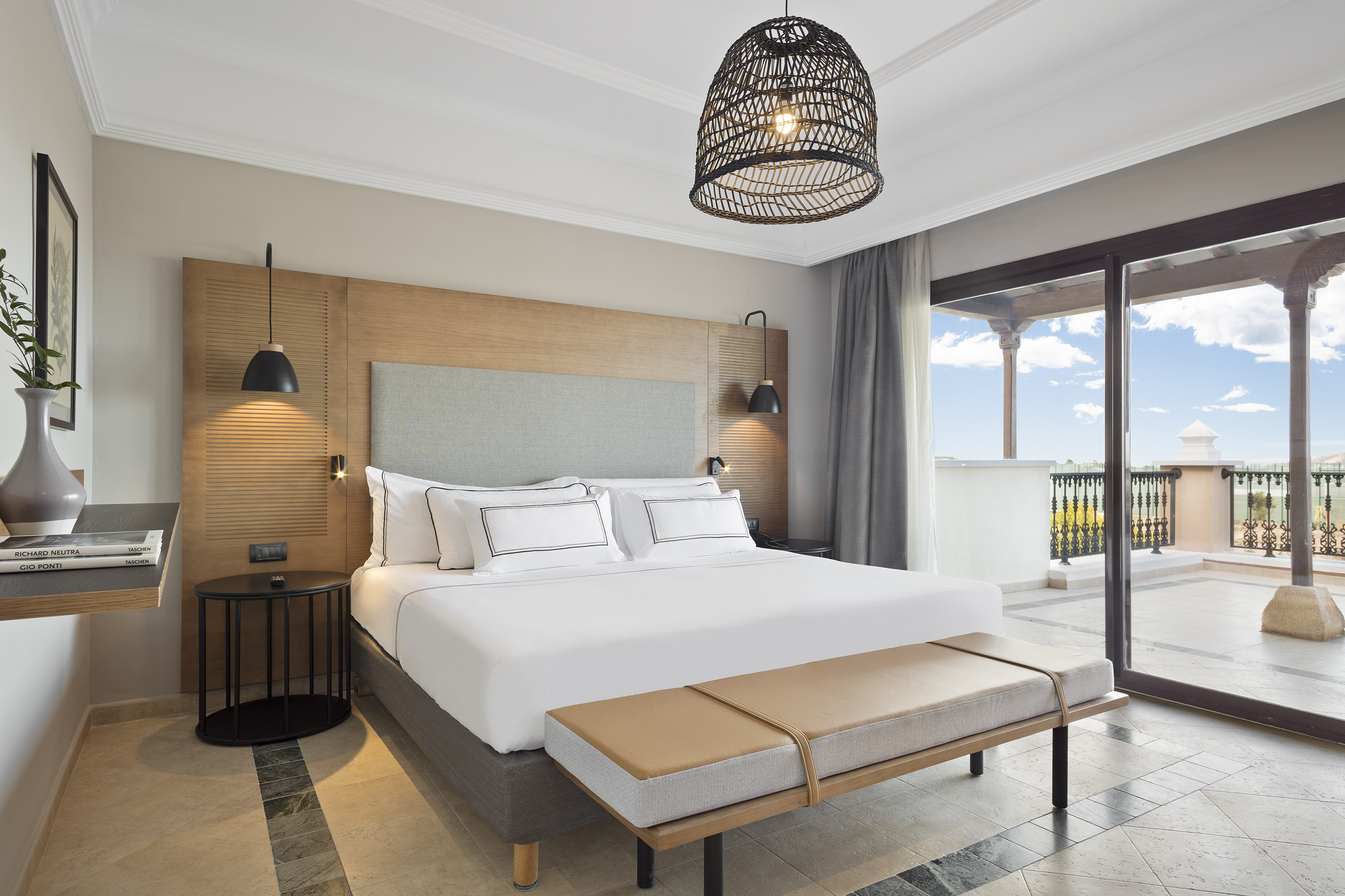 Spacious hotel bedroom with king bed, modern decor, and balcony.