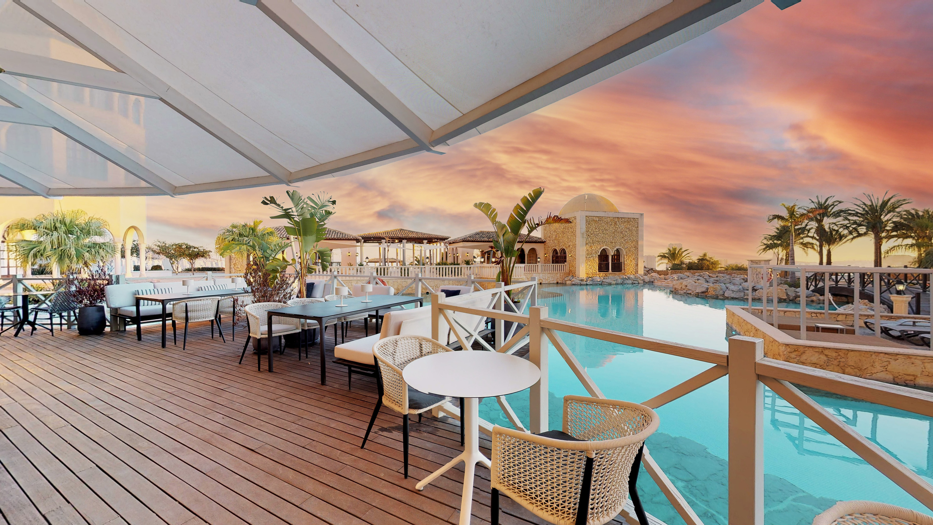 Luxury resort terrace dining, poolside view, Mediterranean building, sunset sky.