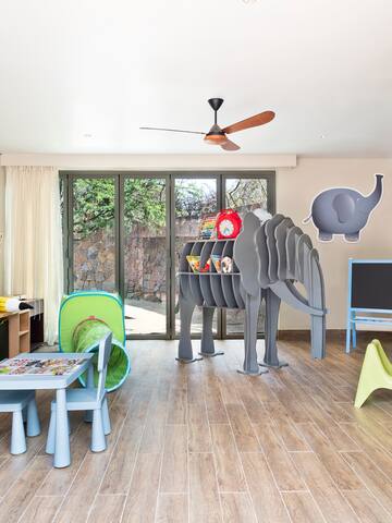 a room with a large elephant sculpture and kids furniture