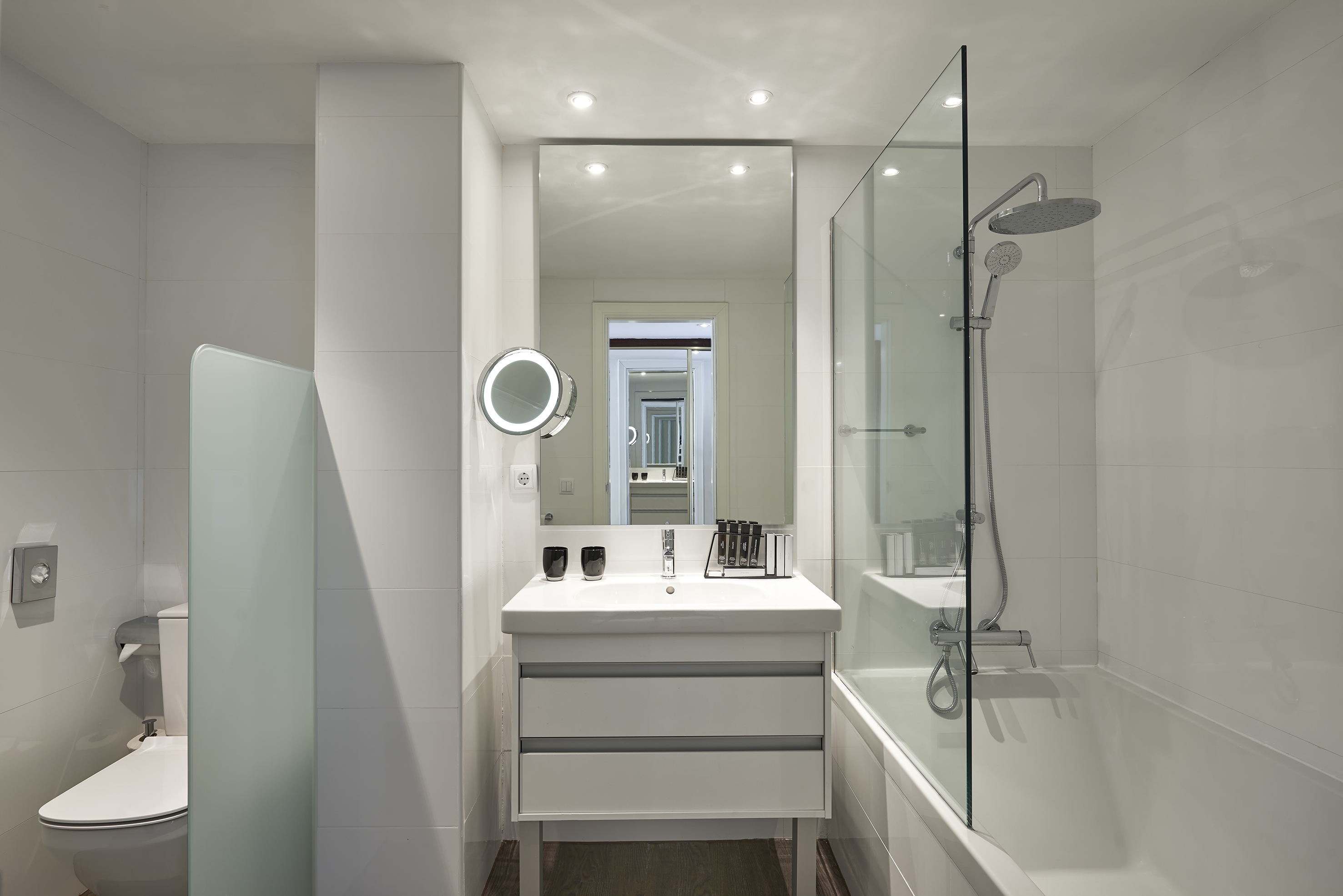 Contemporary white bathroom with vanity, bathtub-shower, and toilet.