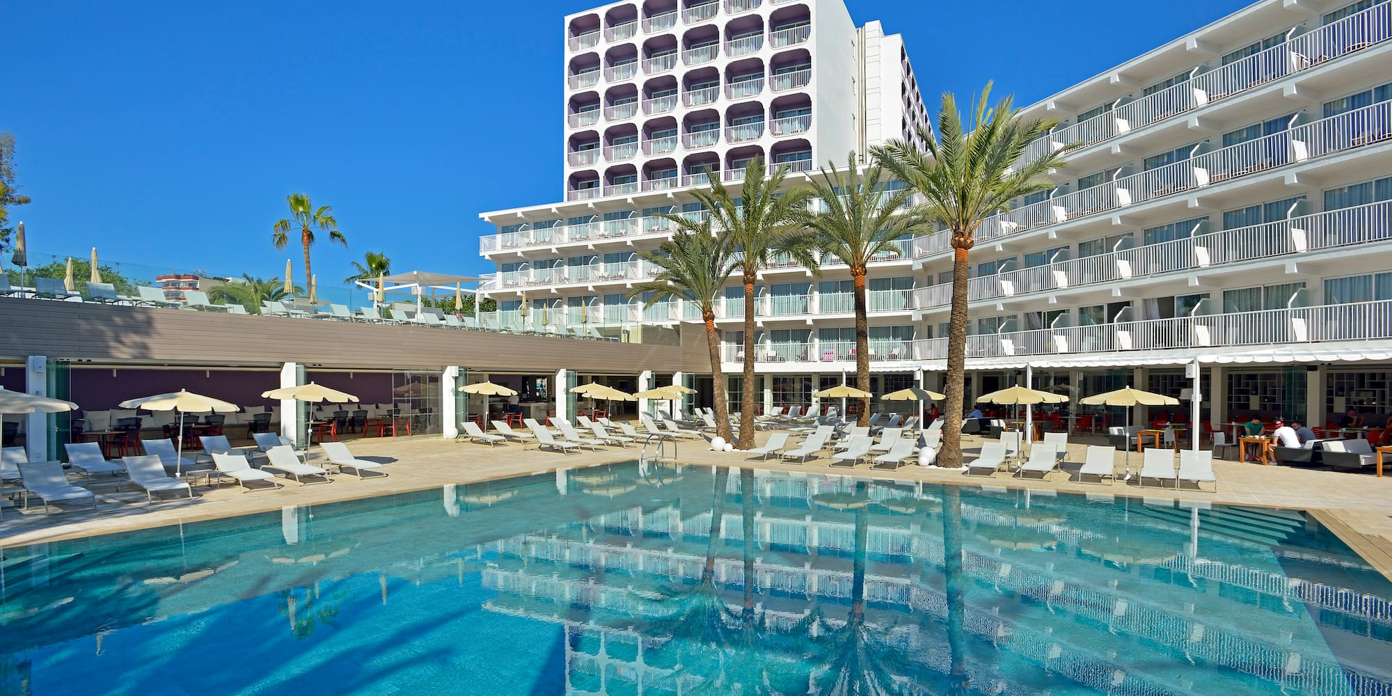 a pool with palm trees and a building