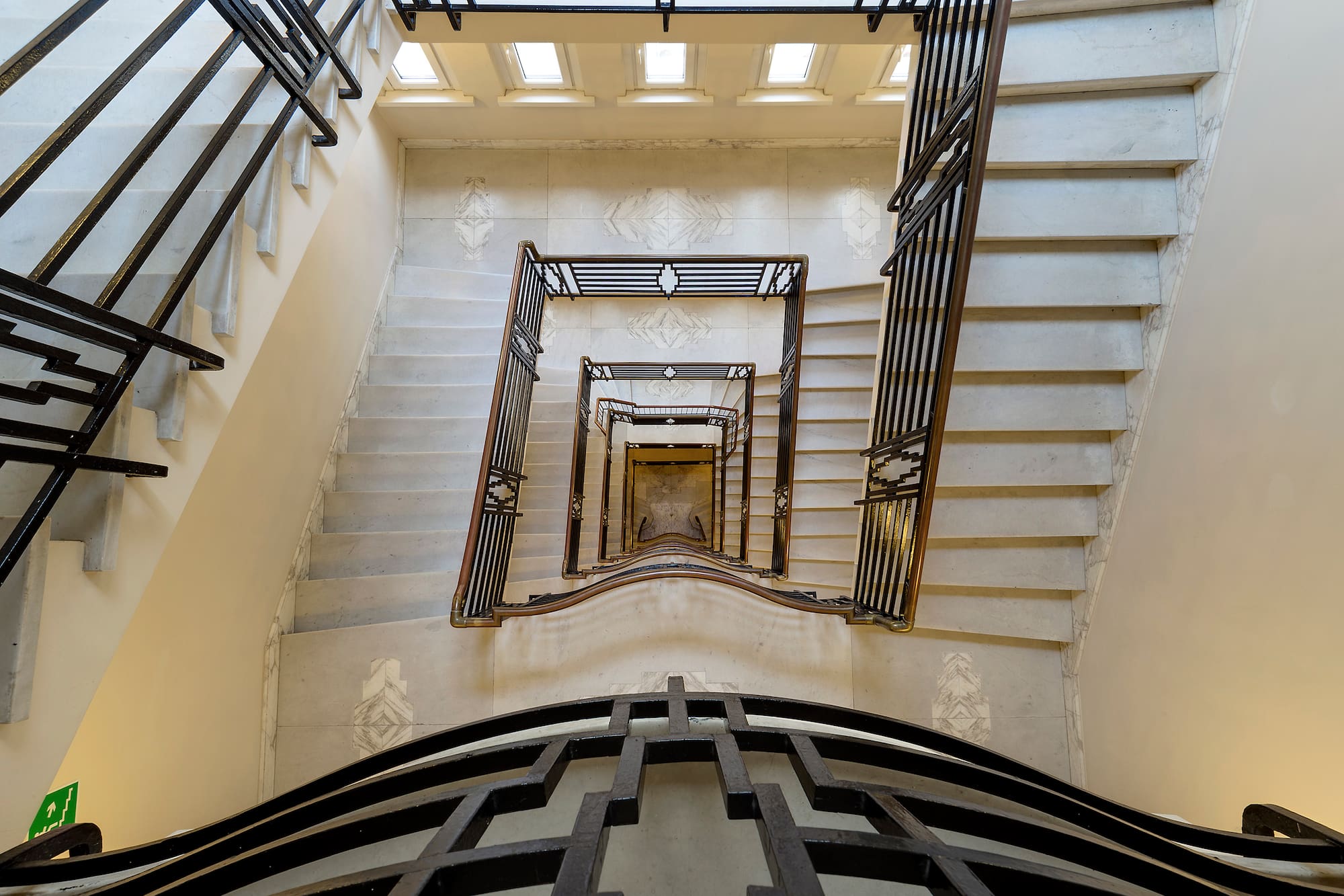 Art Deco spiral marble staircase with geometric metal railings.