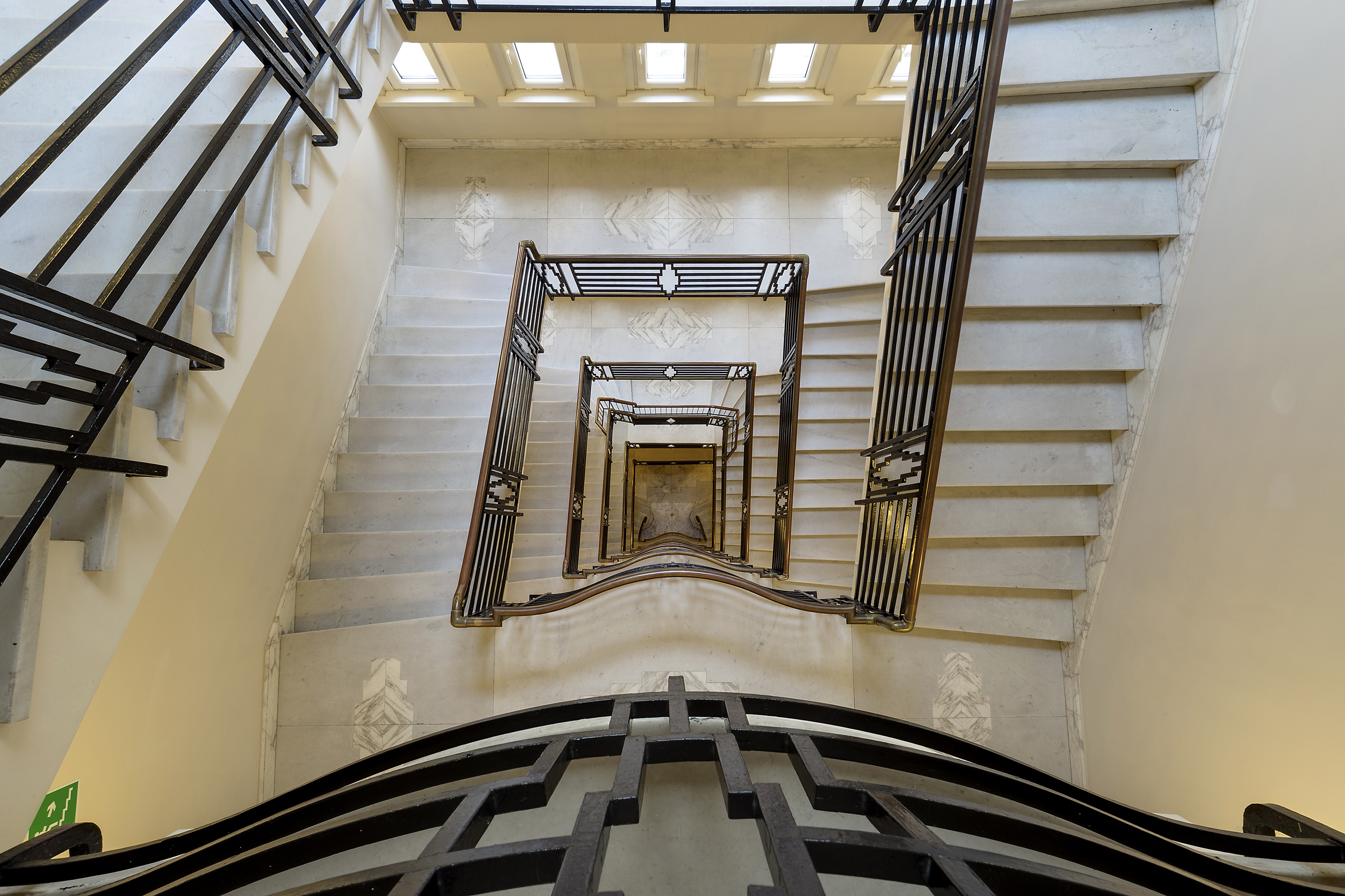 Art Deco spiral marble staircase with geometric metal railings.