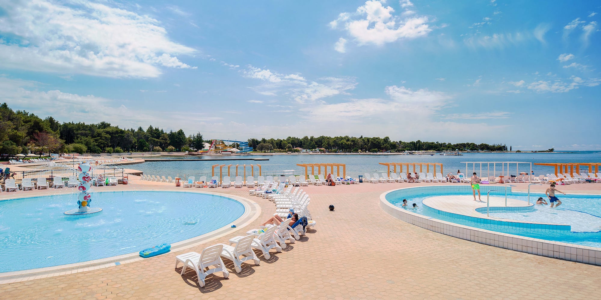 a pool with chairs and a body of water