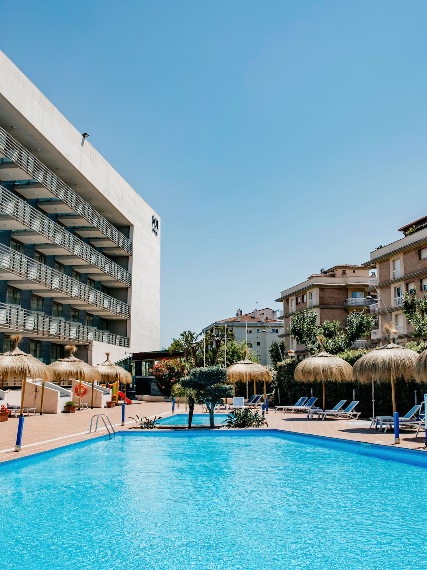 a pool with umbrellas and chairs in front of a building