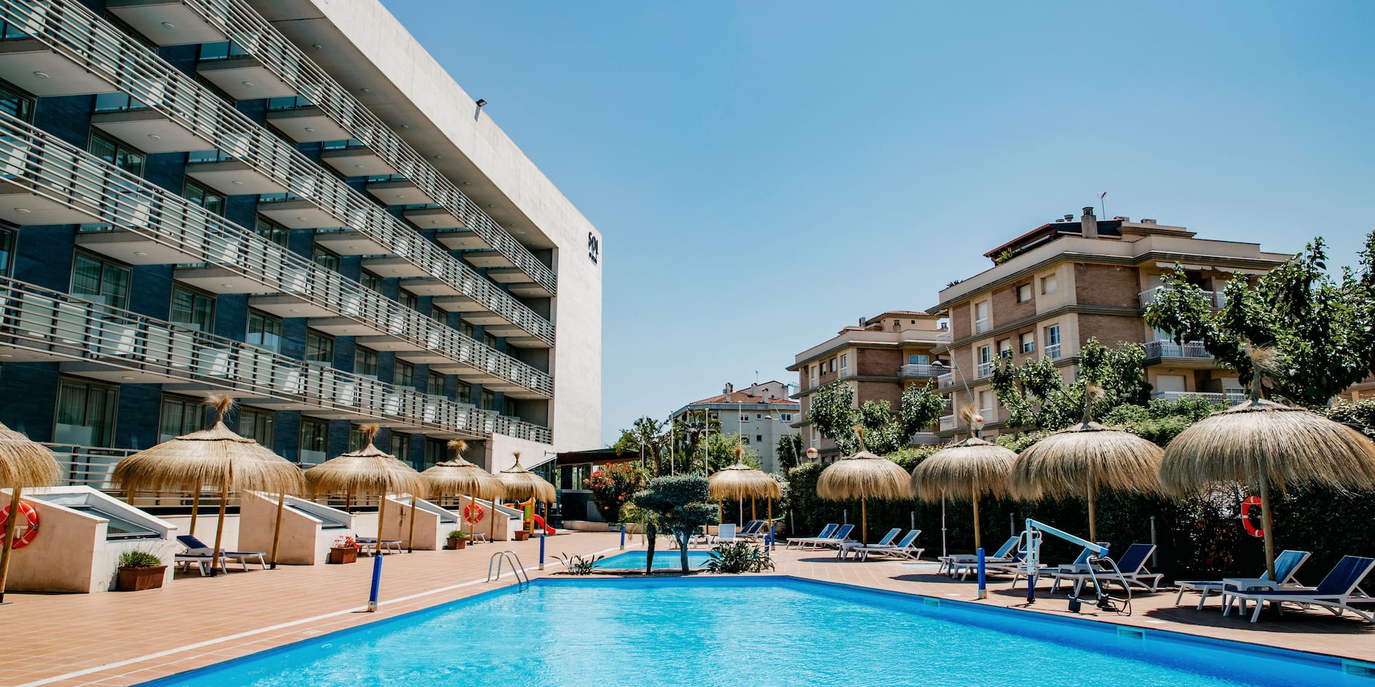 a pool with umbrellas and chairs in front of a building
