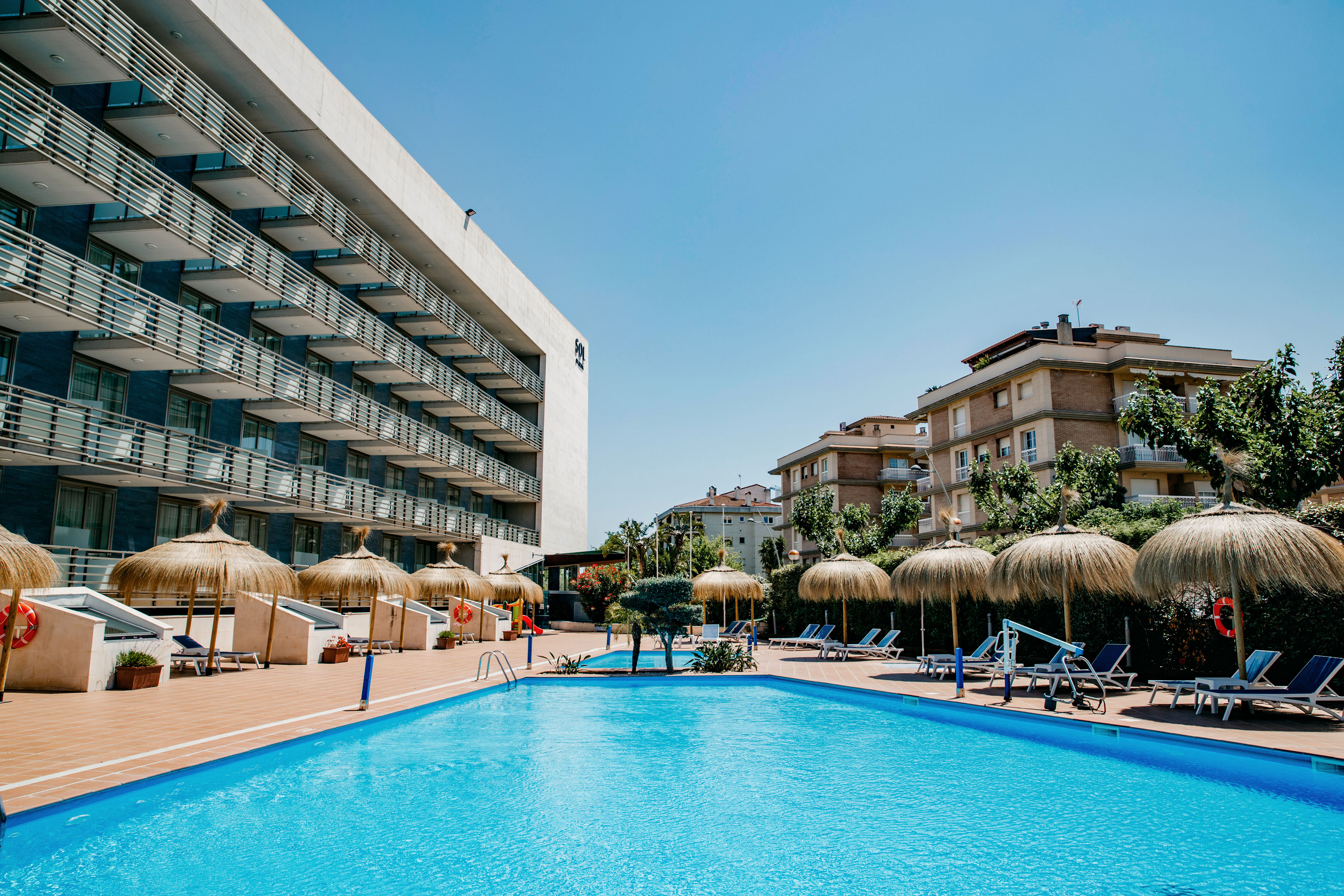 a pool with umbrellas and chairs in front of a building